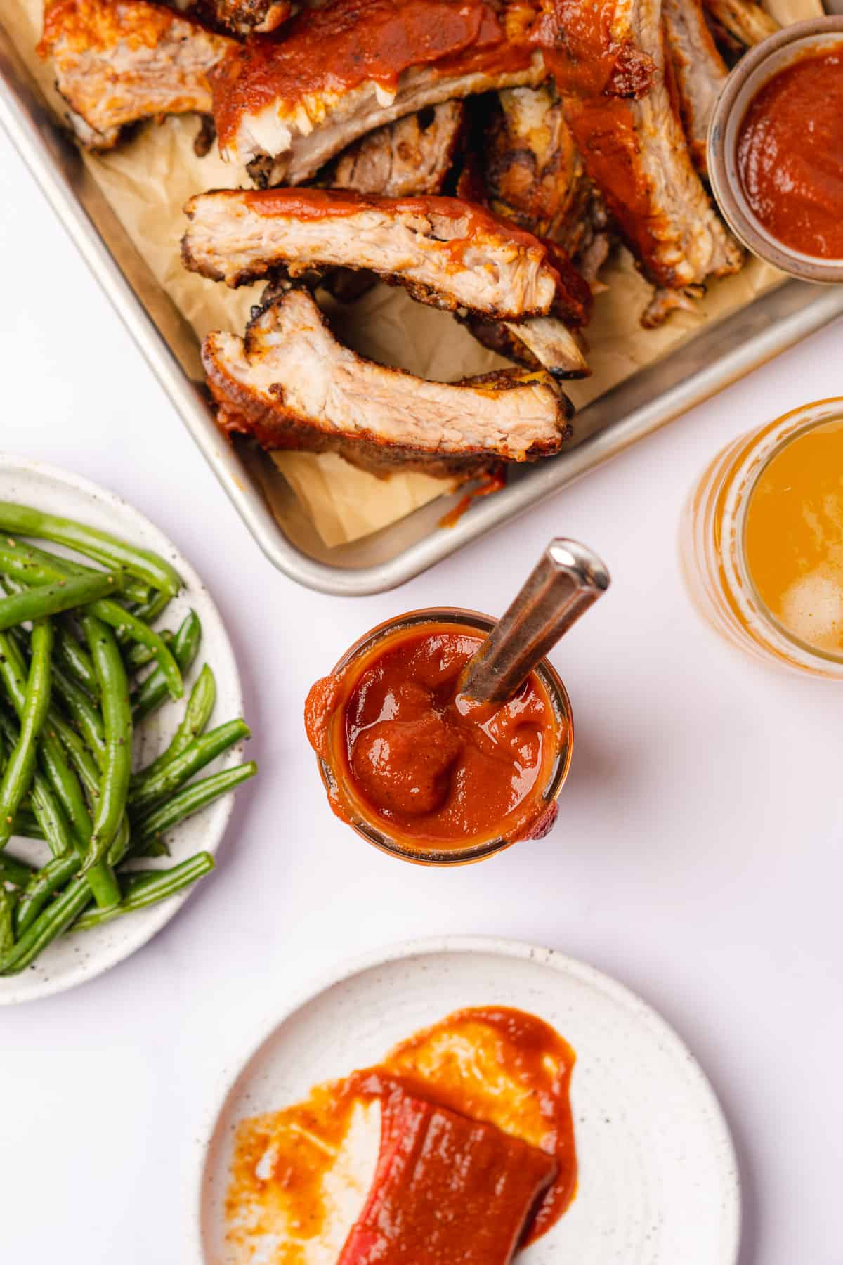 flat lay shot of keto bbq sauce with ribs, green beans and beer