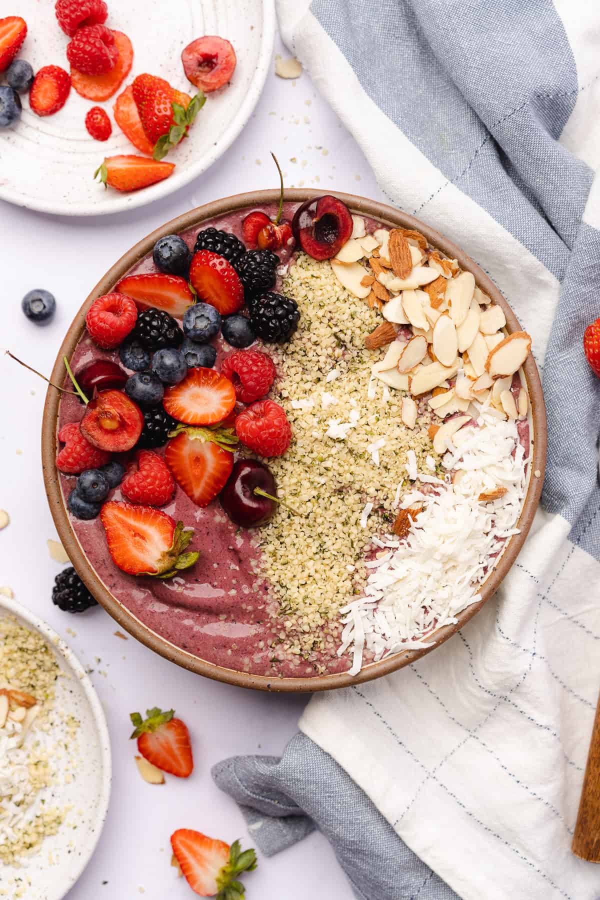 stunning flat lay of a keto acai bowl with fruit toppings, coconut, almonds, and hemp hearts
