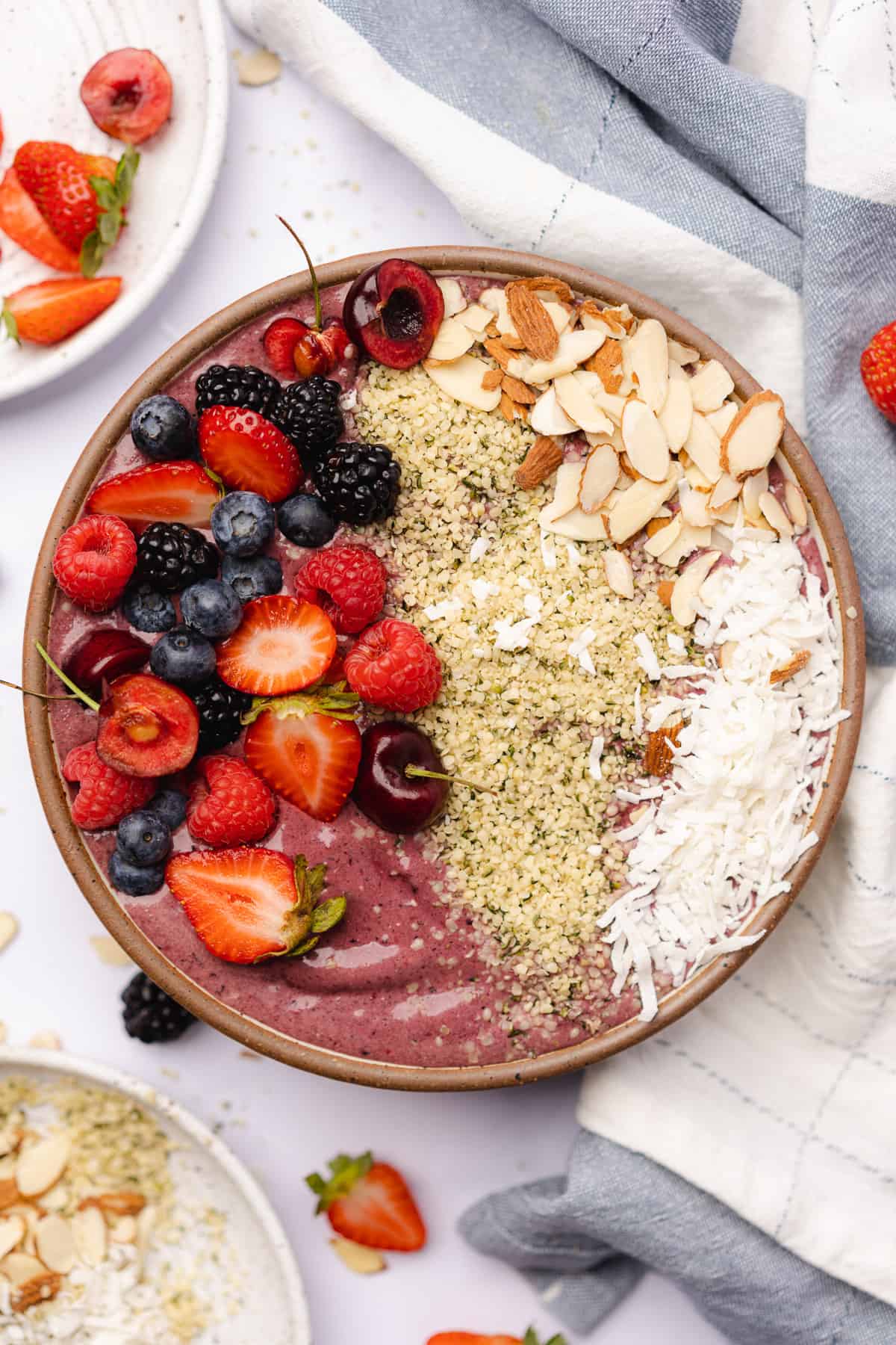 flat lay shot of a large keto acai bowl topped with nuts, seeds, and fruits 