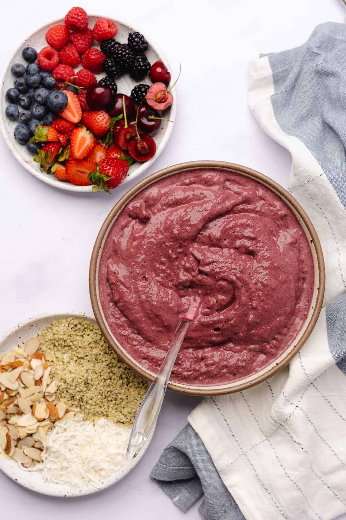 frozen acai puree mixture in a bowl next to fresh berries and toppings