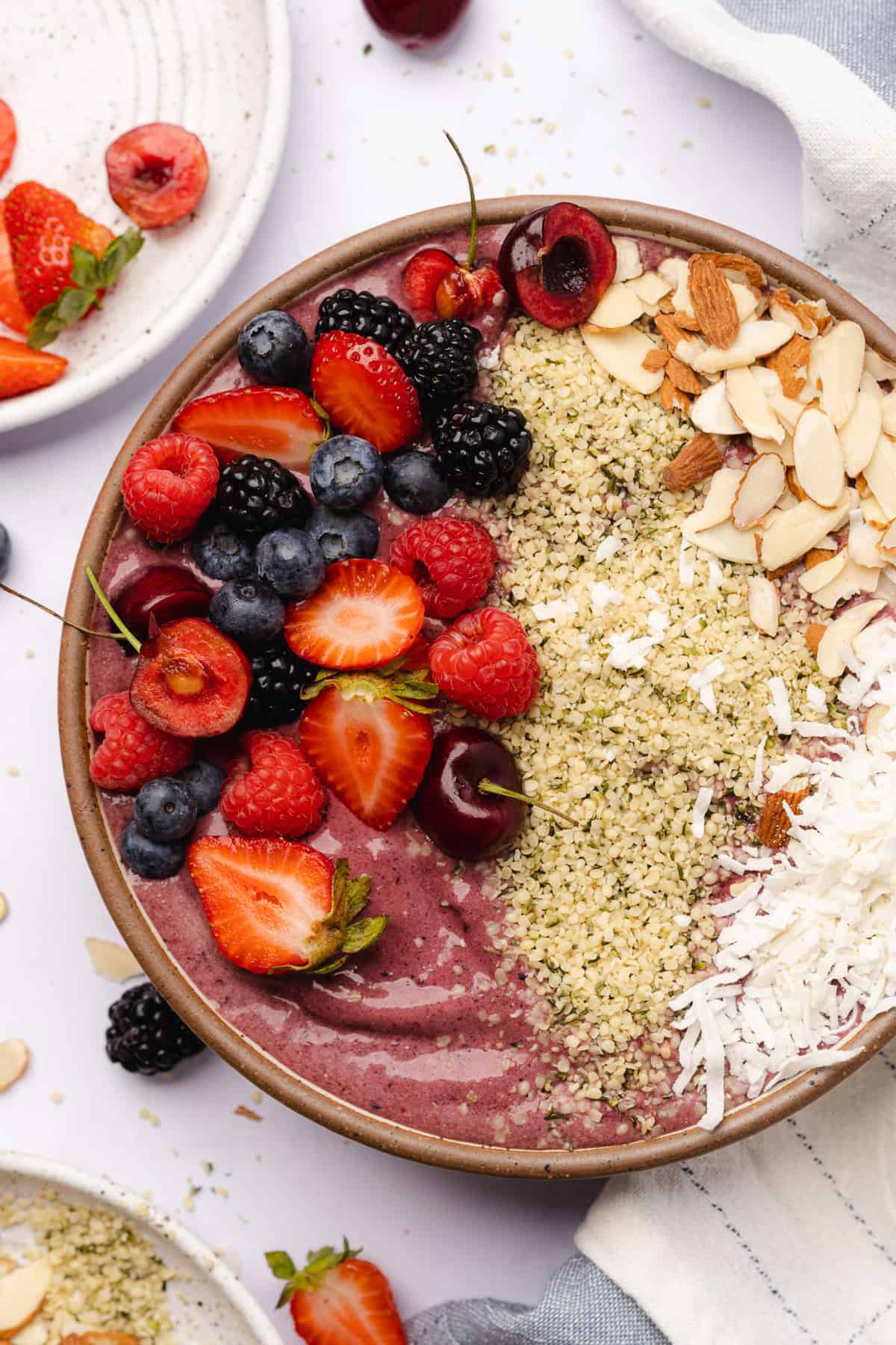 keto acai smoothie bowl topped with low carb berries, coconut flakes, hemp hearts and slivered almonds