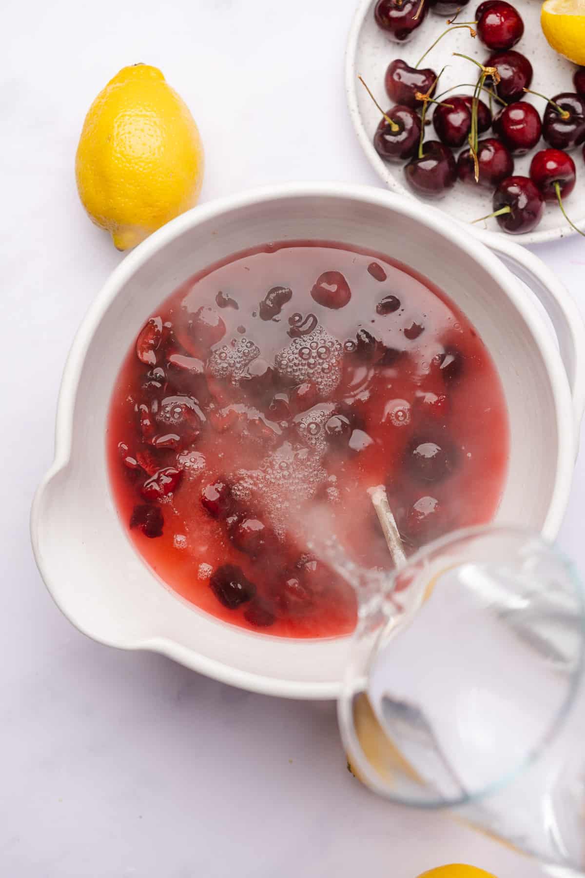 pouring boiling hot water into a bowl of cherries