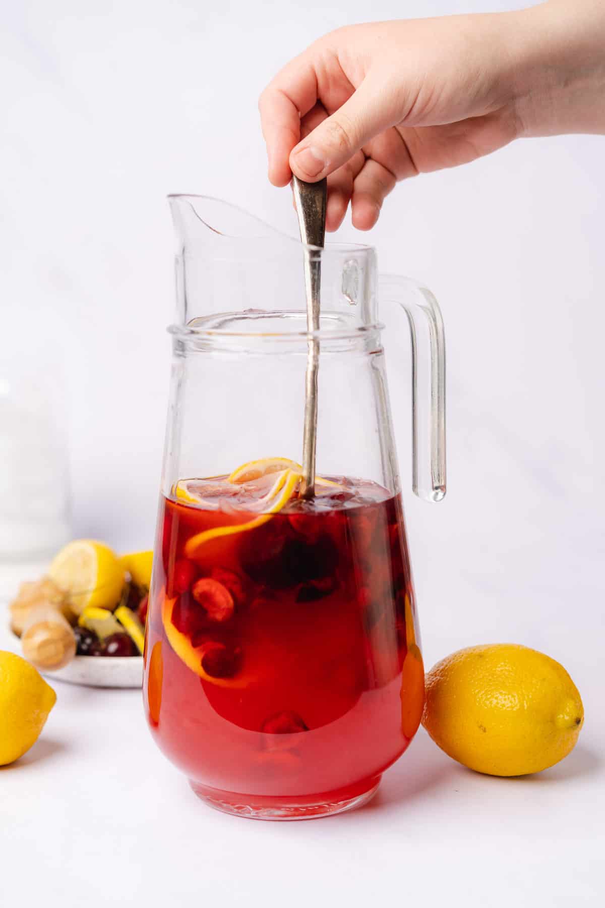 hand stirring a pitcher of cherry lemonade
