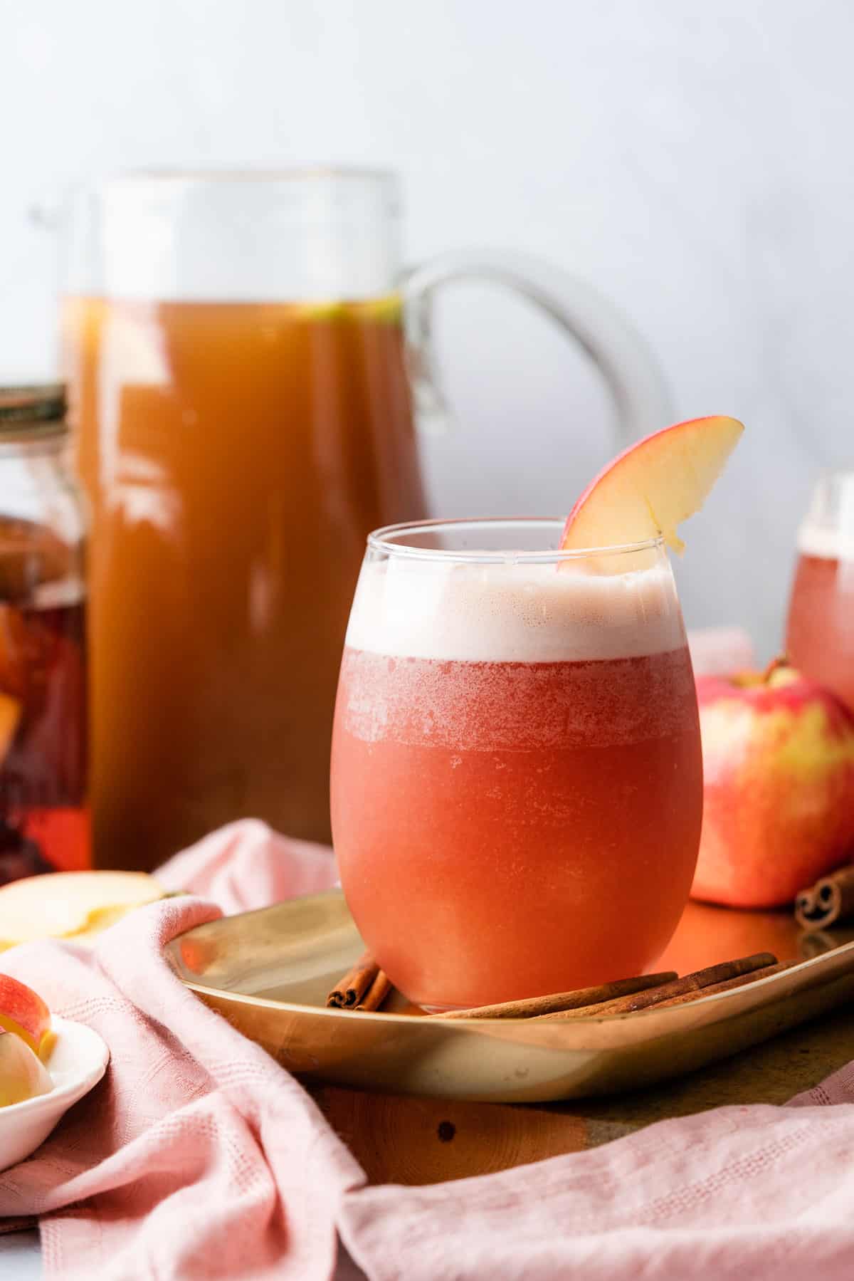 stunning apple cider bourbon cocktail in a stemless wine glass topped with an apple wedge.