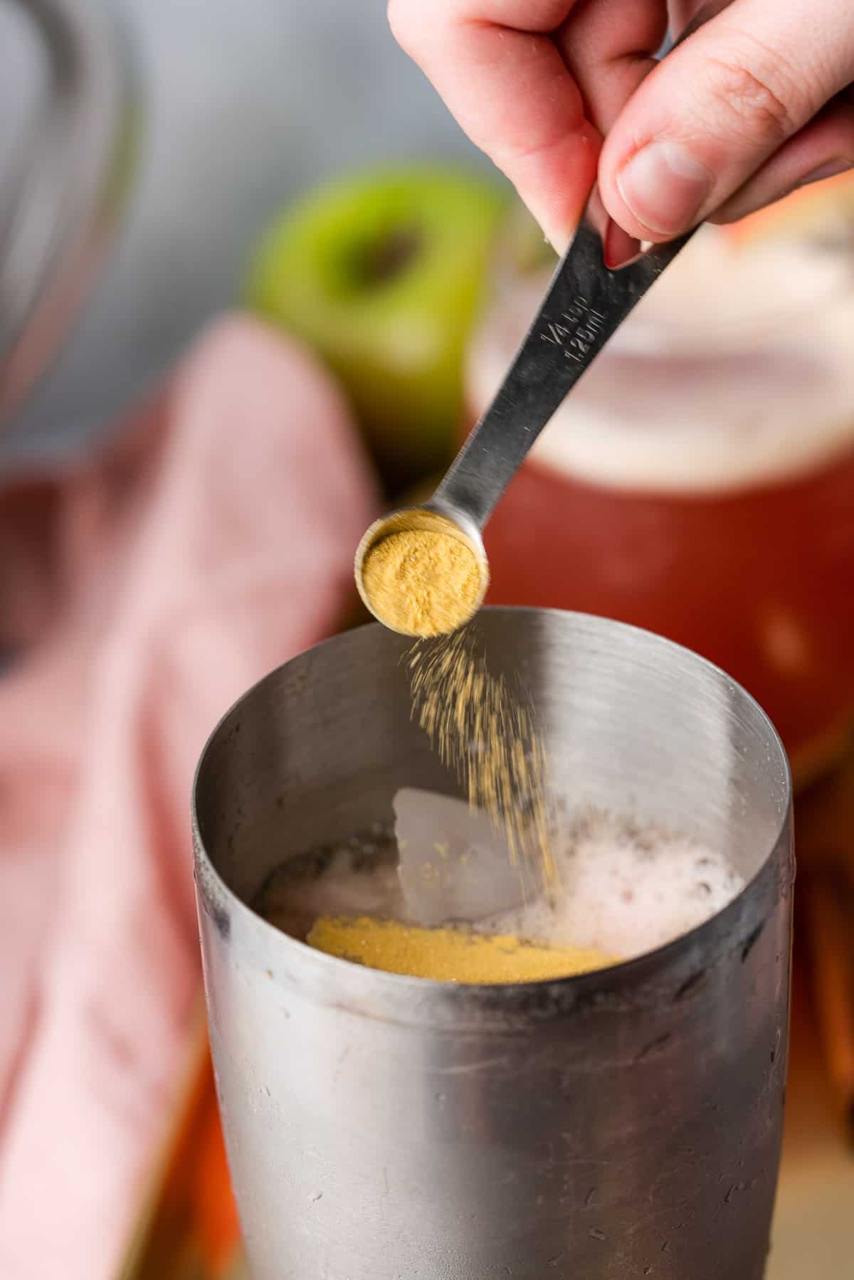 hand pouring edible gold glitter into a cocktail shaker.