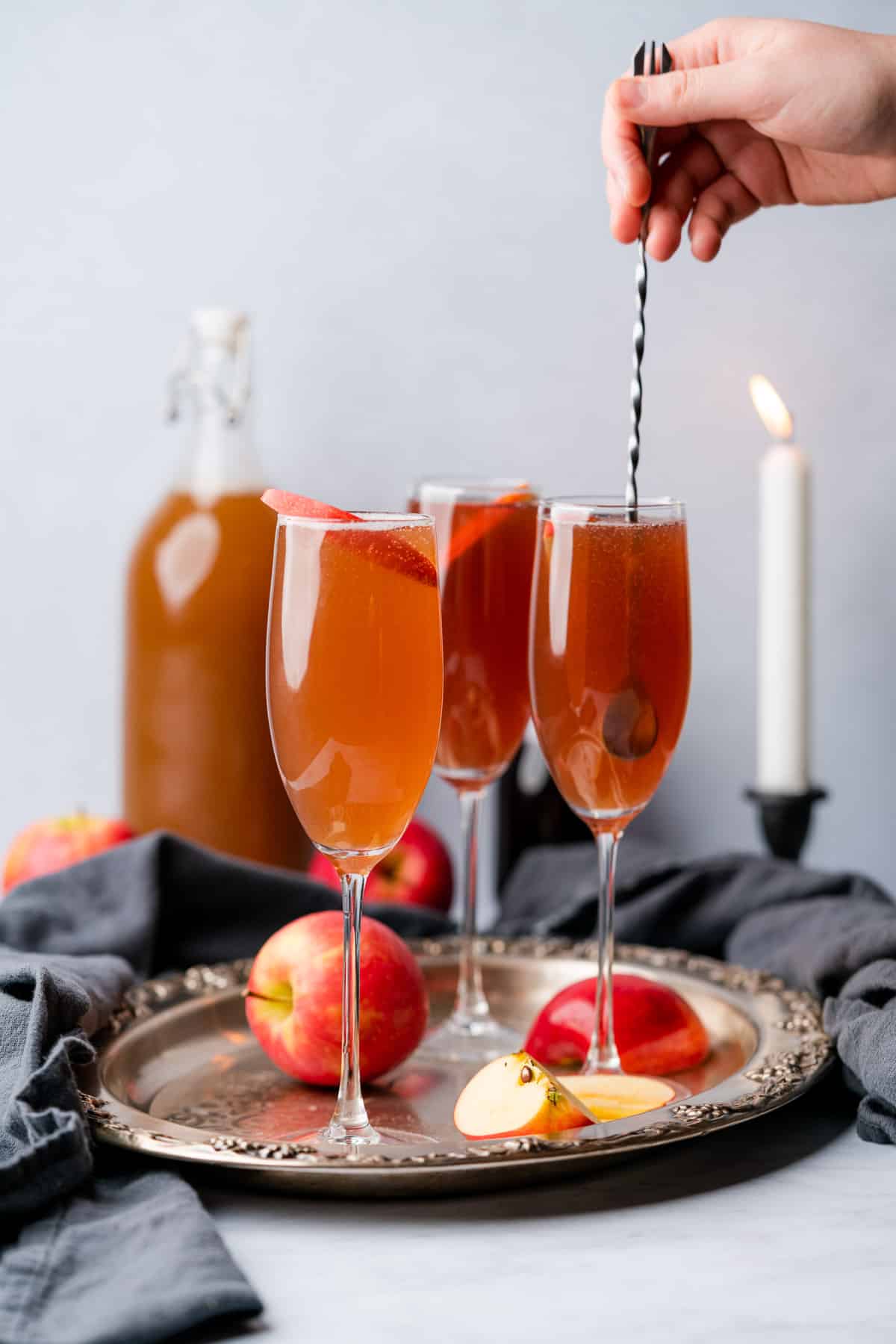 hand stirring a glass of an apple cider mimosa