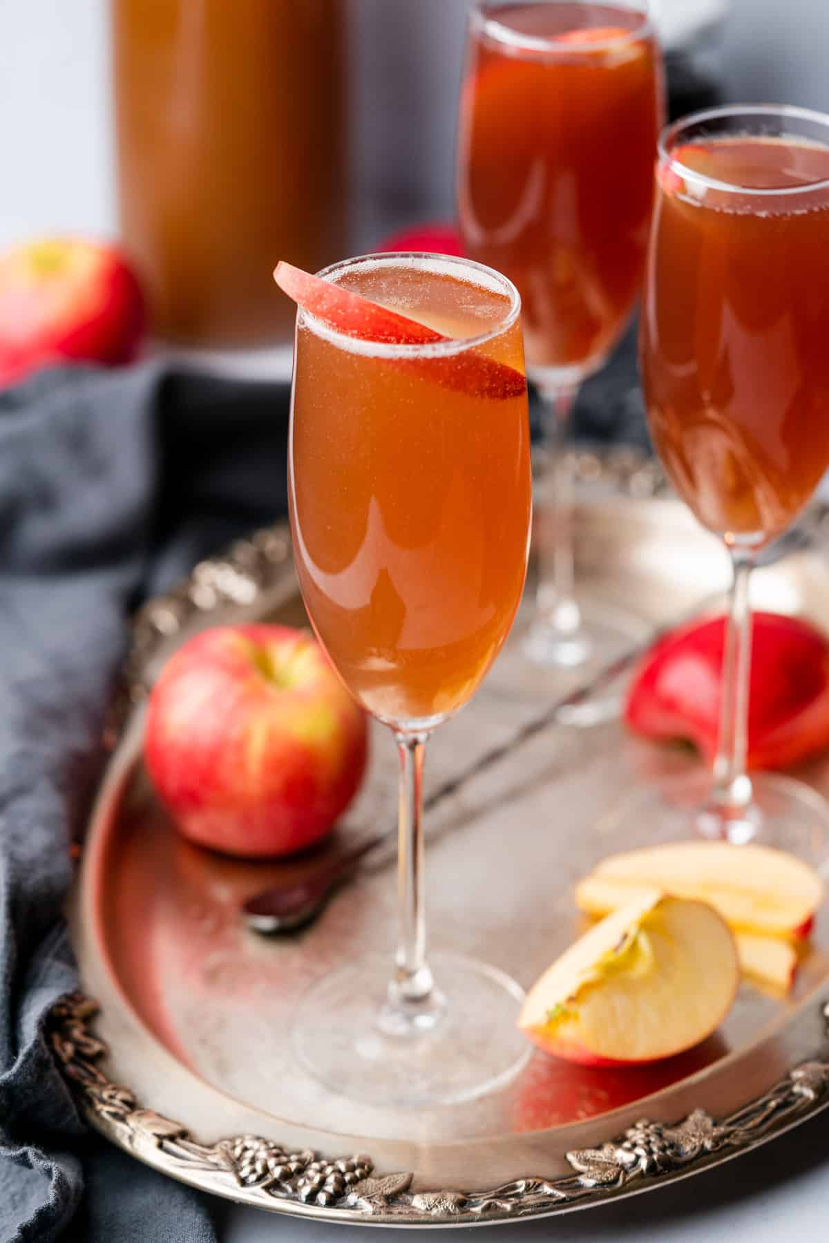 apple cider mimosa zoomed out on a metal serving tray with apples in the background