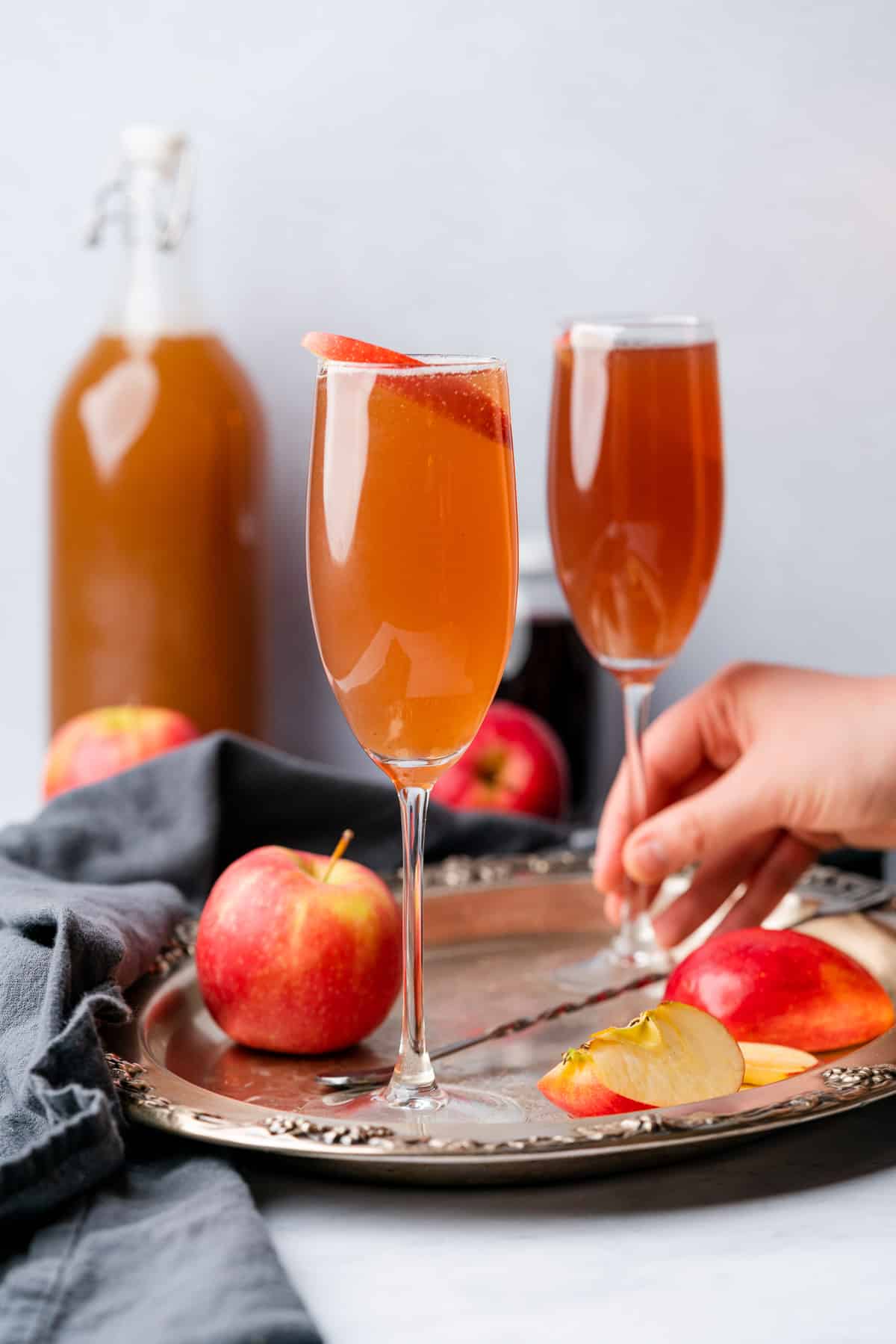 hand grabbing a glass of an apple cider mimosa from a tray of cocktails