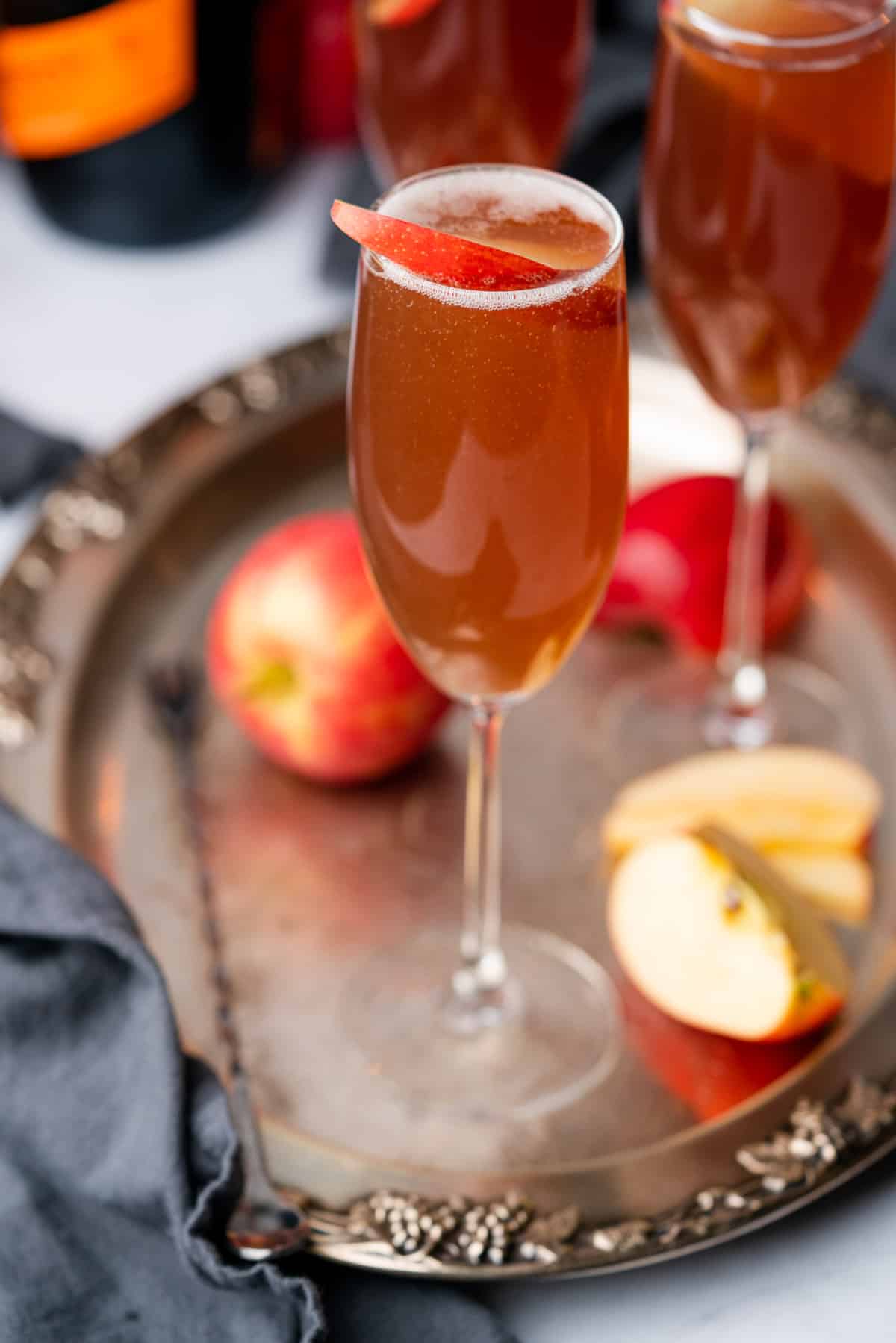 apple cider mimosa on a meal tray surrounded by fresh apples