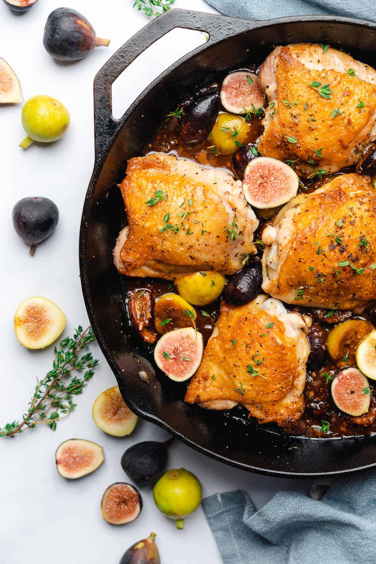 balsamic fig glaze chicken in a cast iron skillet surrounded by fresh figs and thyme