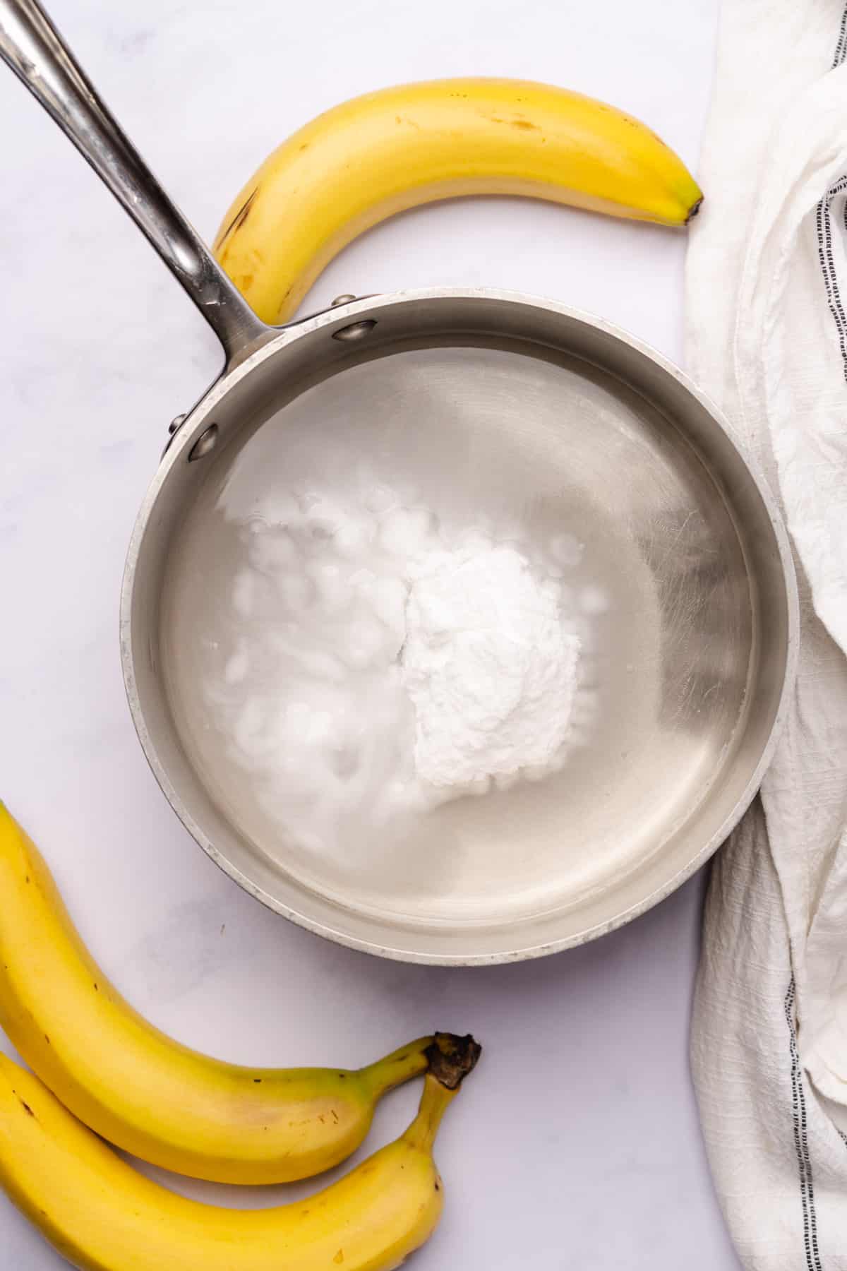 water with allulose added in a sauce pan surrounded by bananas