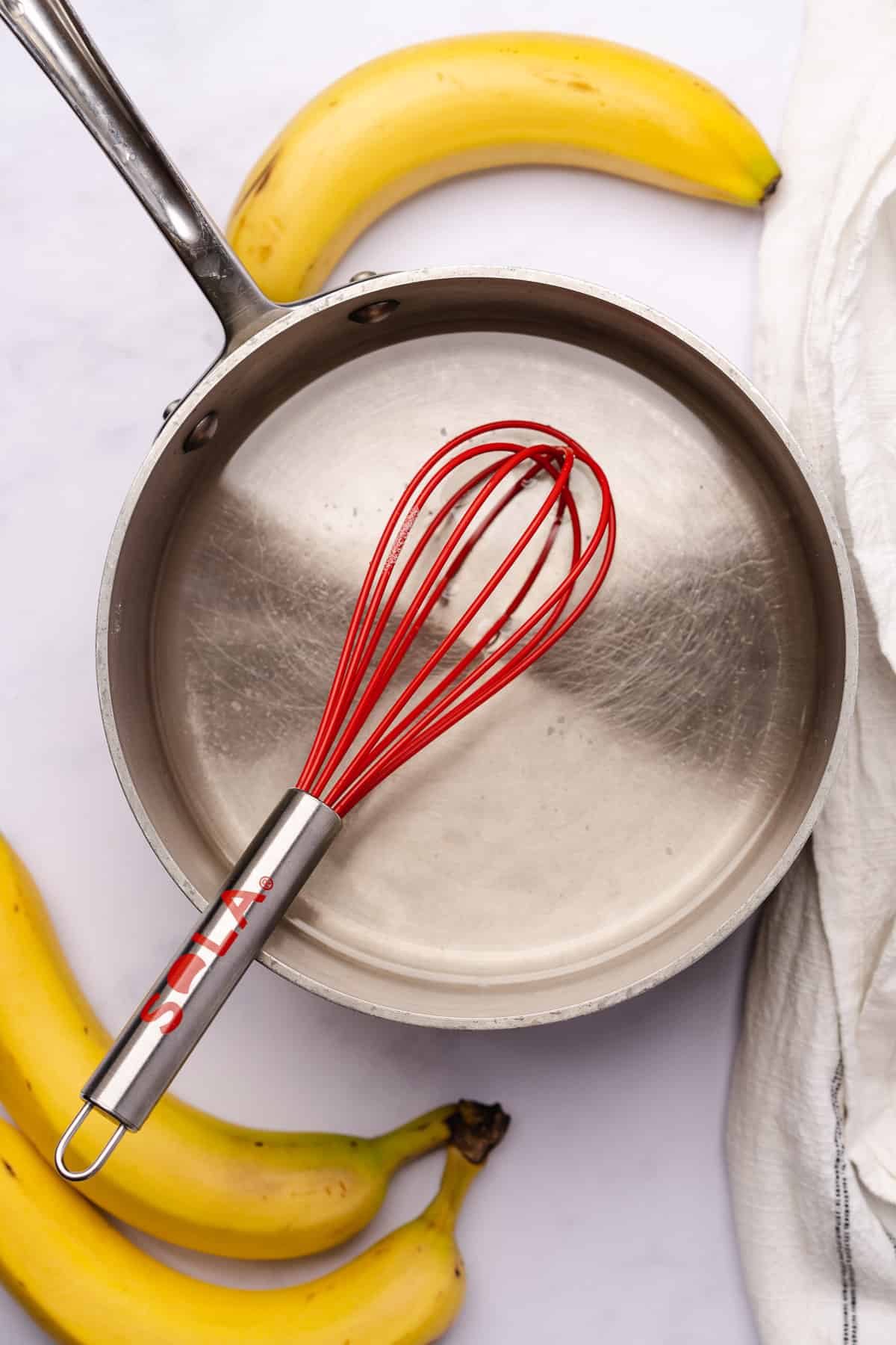 red silicone whisk inside of a saucepan with dissolved sweetener 