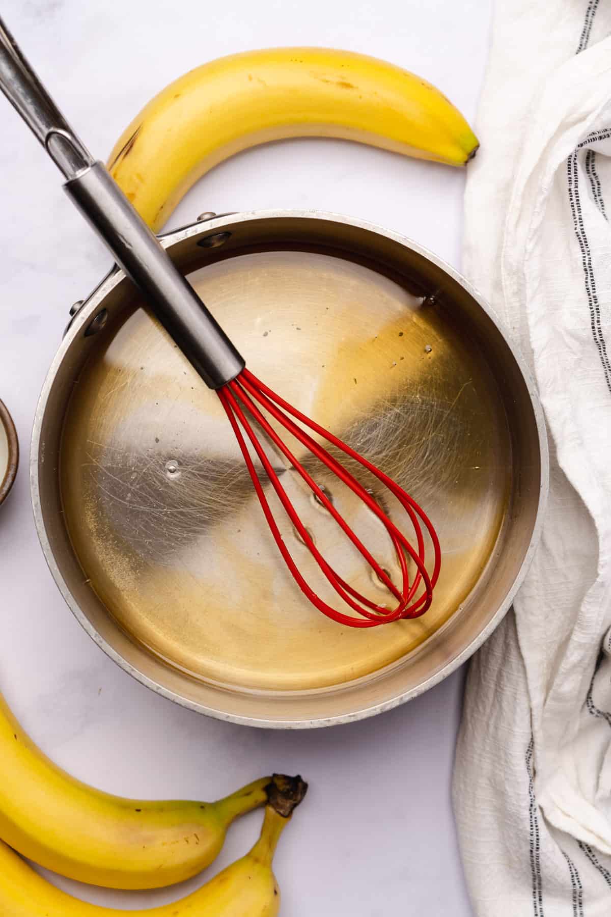 vanilla extract stirred into water with allulose with a red silicone whisk 