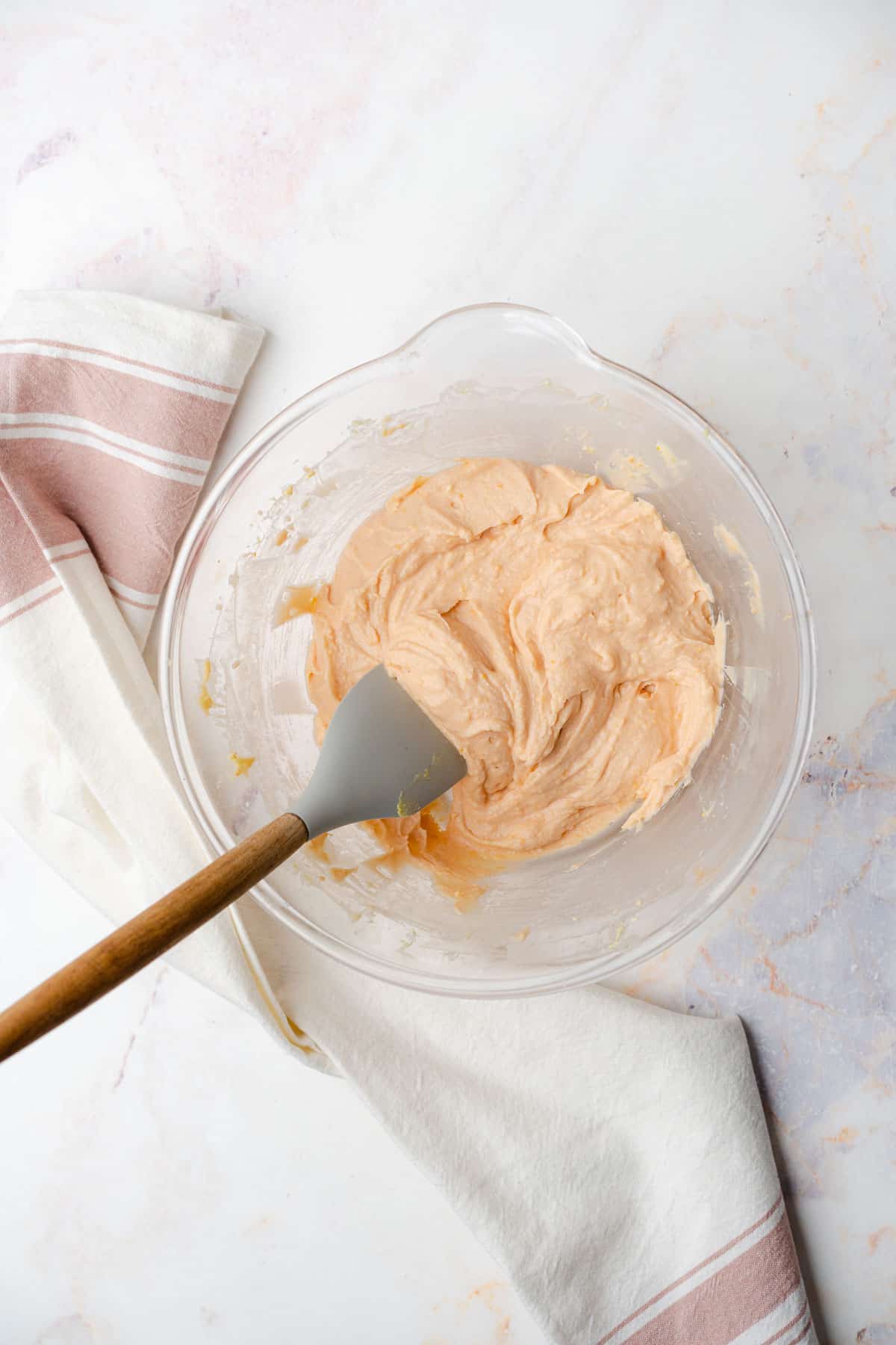 rubber spatula mixing together blood orange cream cheese frosting