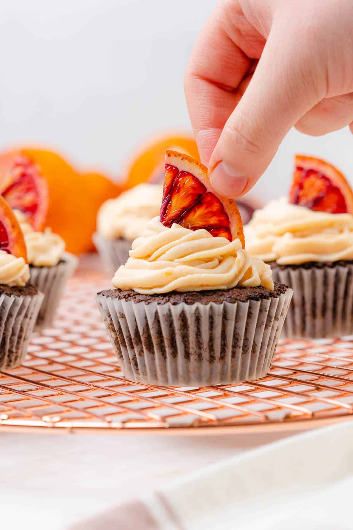 placing a piece of blood orange onto a cupcake