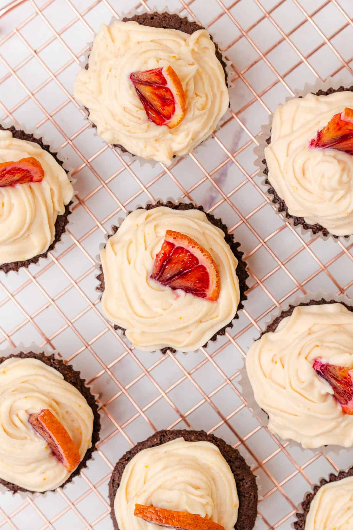 flat lay of orange chocolate cupcakes topped with blood orange pieces