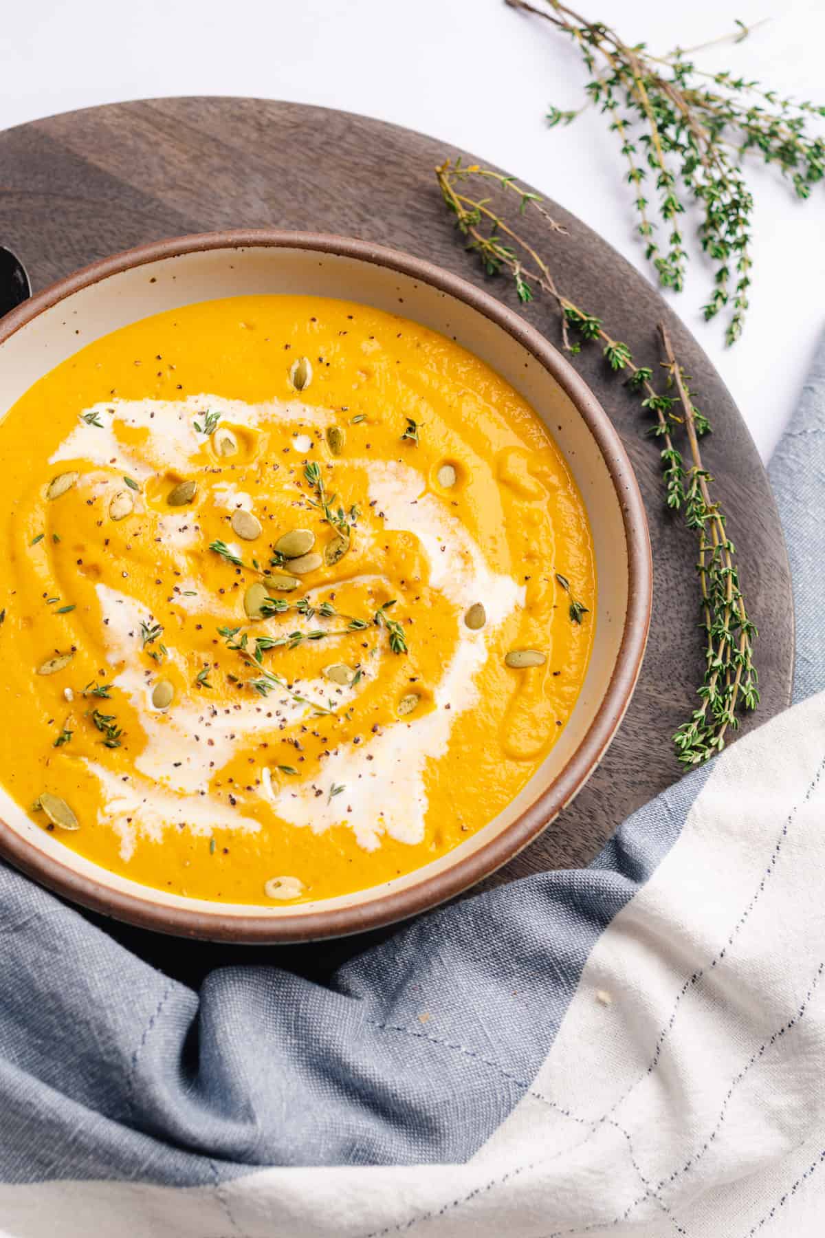 pumpkin soup drizzled with heavy cream and topped with pepitas, fresh thyme and black pepper
