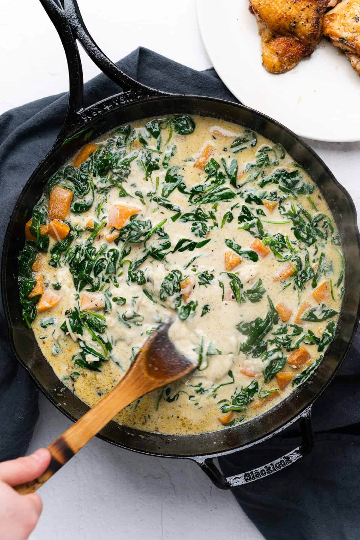 stirring butternut squash and spinach parmesan sauce