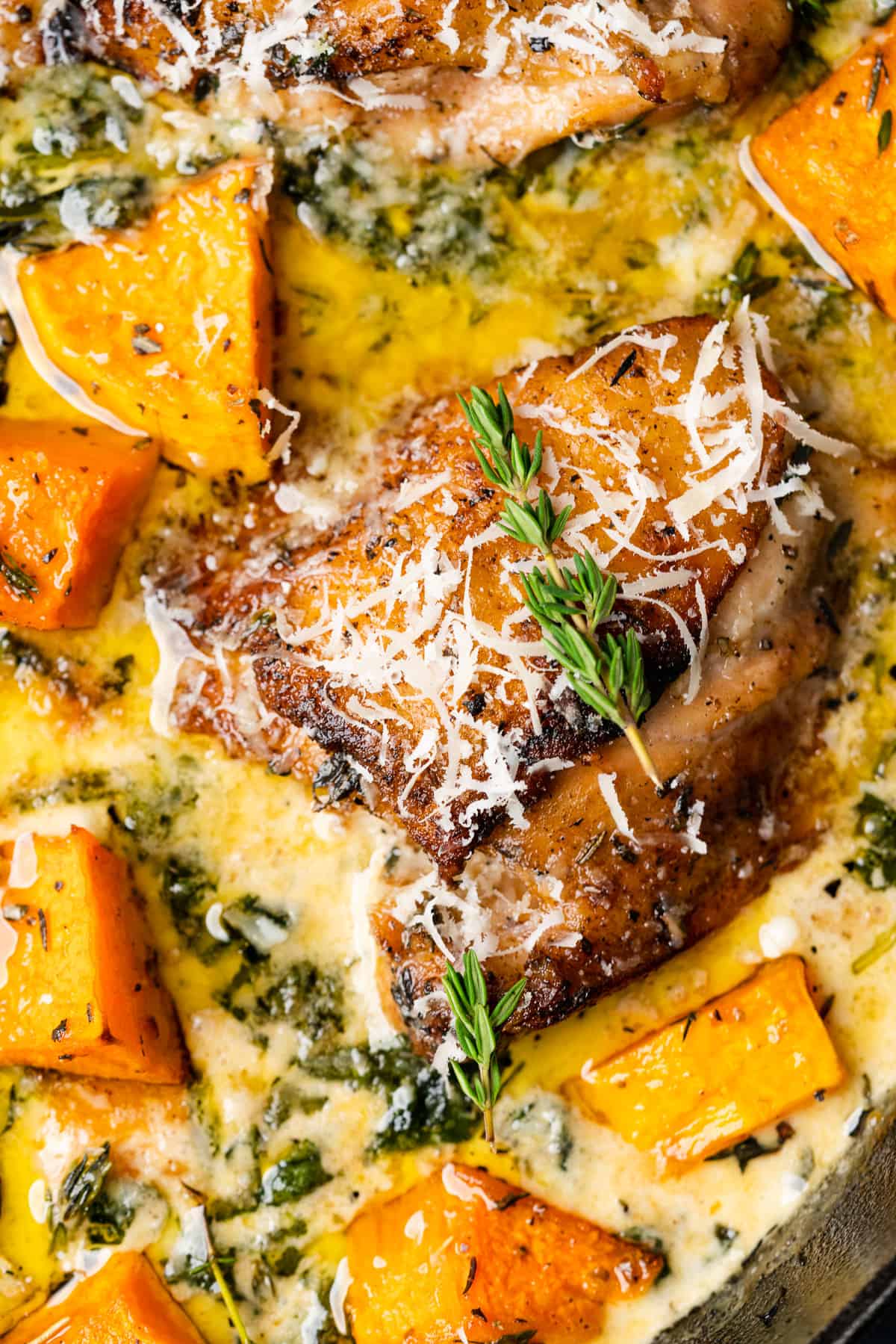 Close up of chicken thigh simmering in garlic parmesan sauce