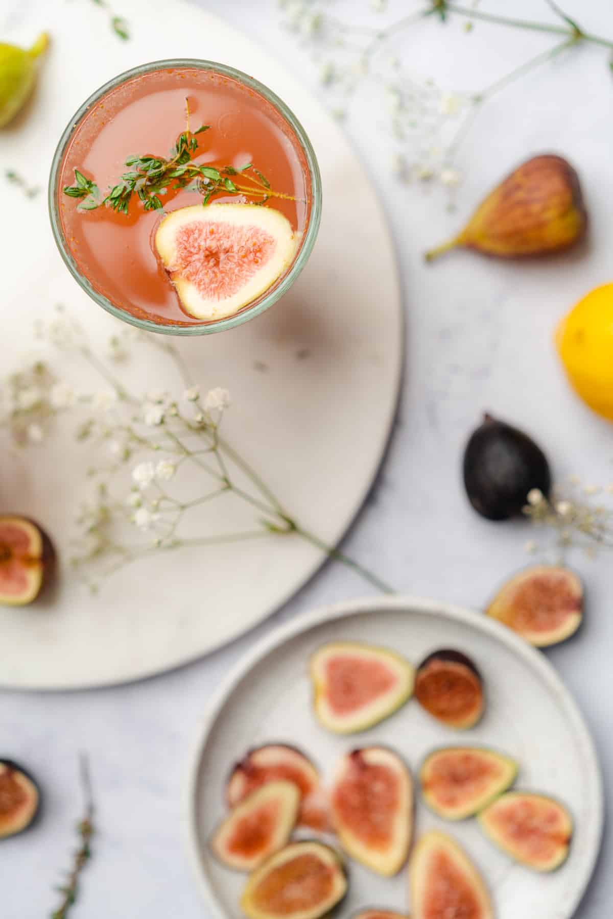 gorgeous fig cocktail with fresh figs and baby's breath flowers surrounding the glass