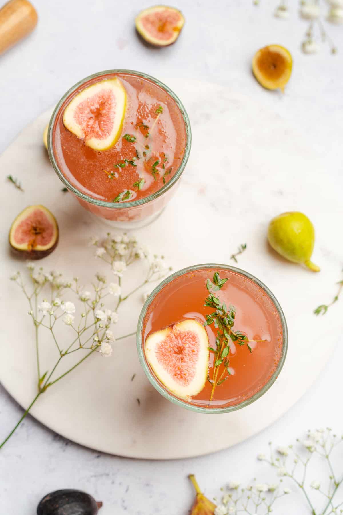 two fig cocktails surrounded by fresh figs and baby's breath 