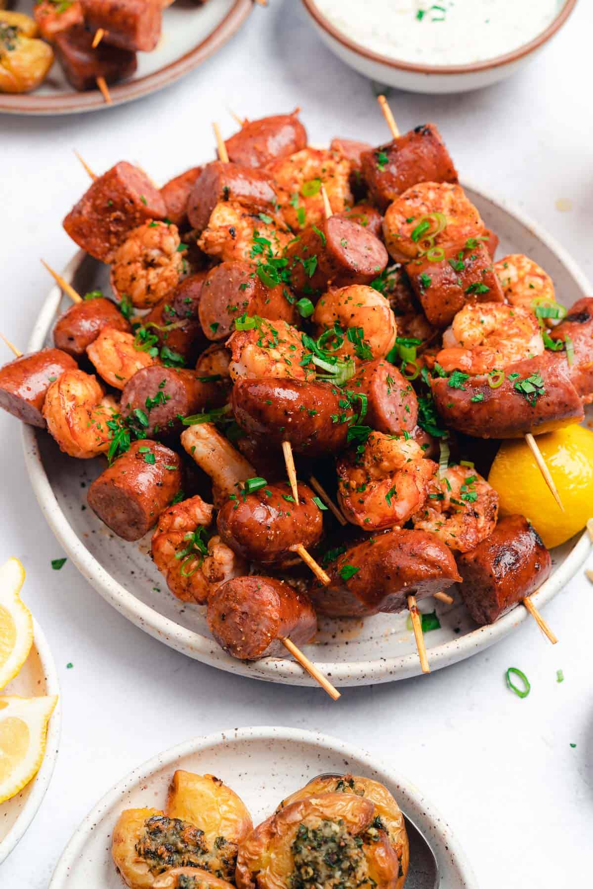 grilled smoked sausage and shrimp skewers on a plate with lemon, parsley and shrimp skewers