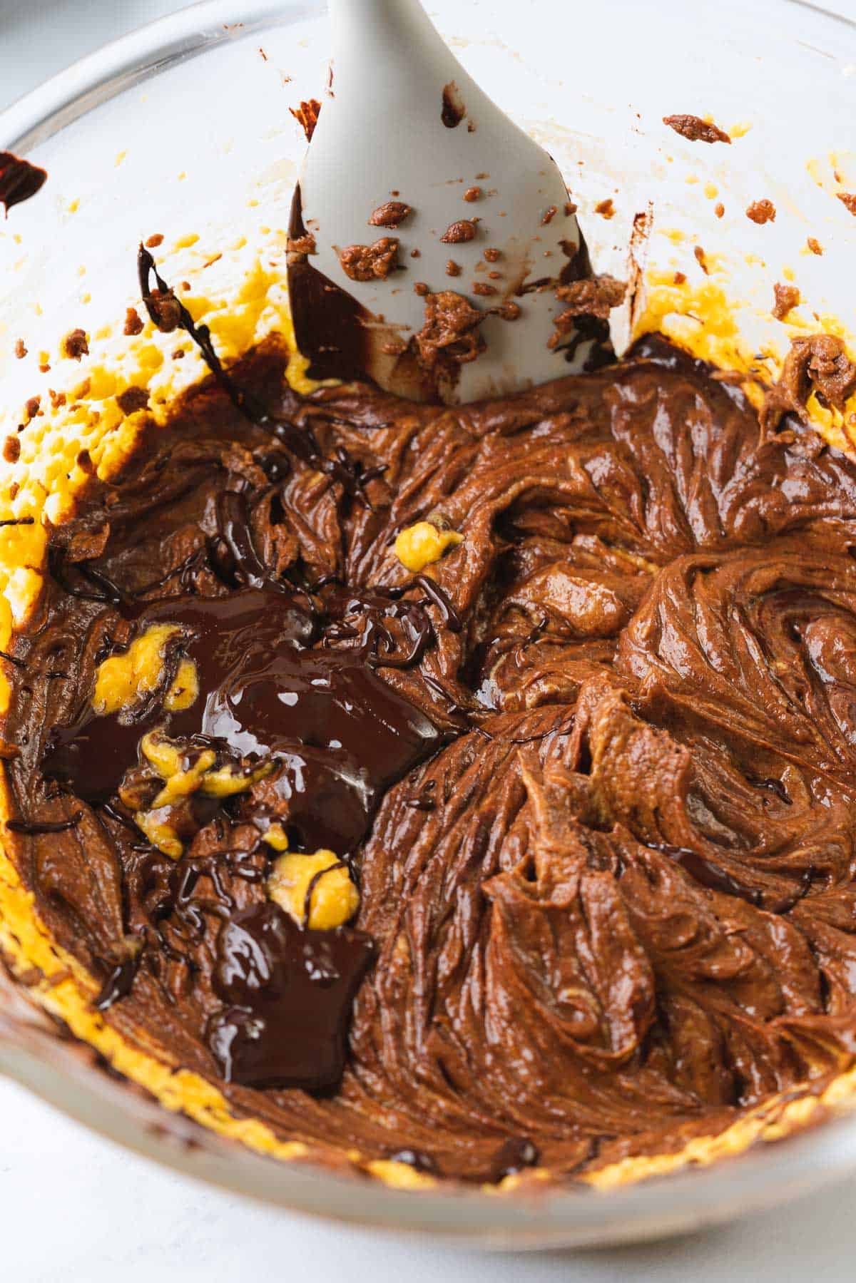 mixing melted chocolate into pumpkin brownie batter