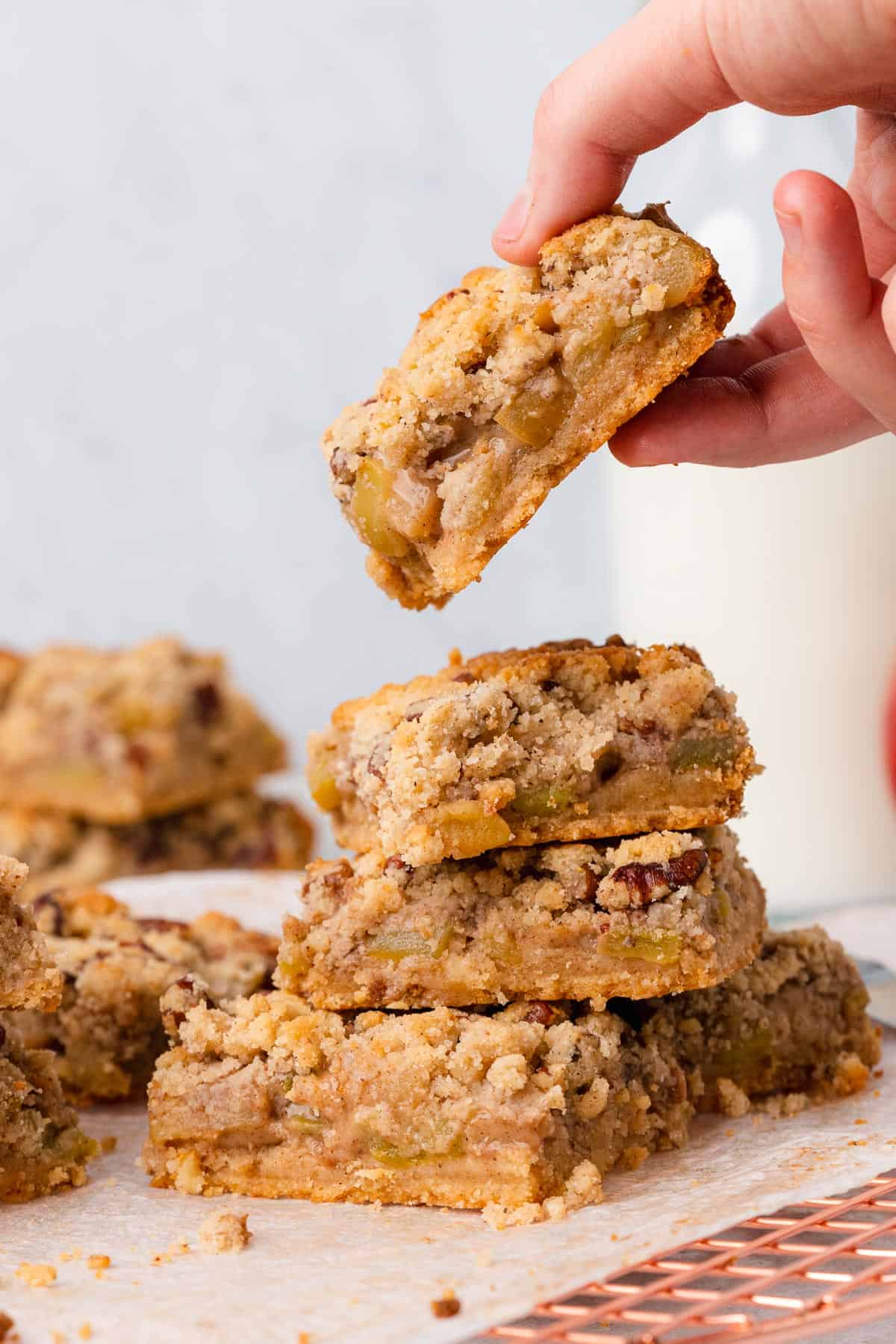 hand picking up a keto apple crumble bar off a stack of bars