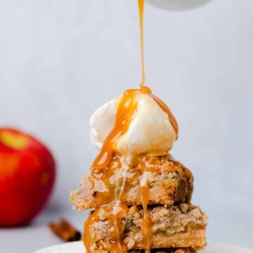 pouring salted caramel syrup on a stack of apple bars