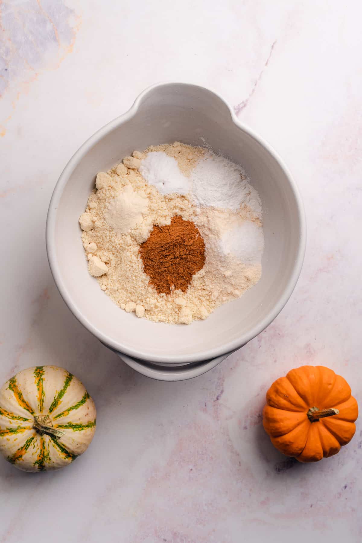 dry ingredients to make pumpkin bars in a ceramic bowl sectioned off with different ingredients