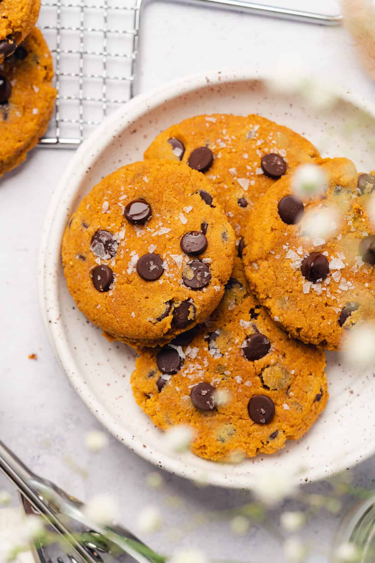 keto pumpkin chocoalte chip cookies on a plate with baby's breath flowers