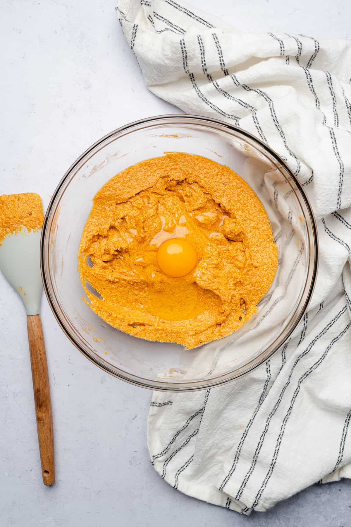 pumpkin puree cookie batter with an egg in the batter to be mixed