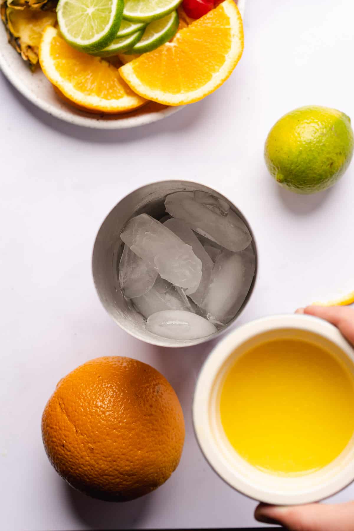 adding pineapple juice to an ice filled cocktail shaker