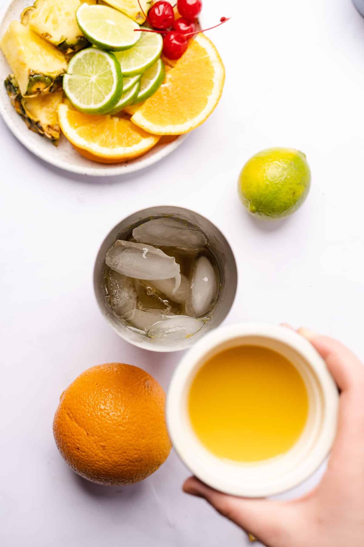 fresh squeezed orange juice being added to a cocktail shaker