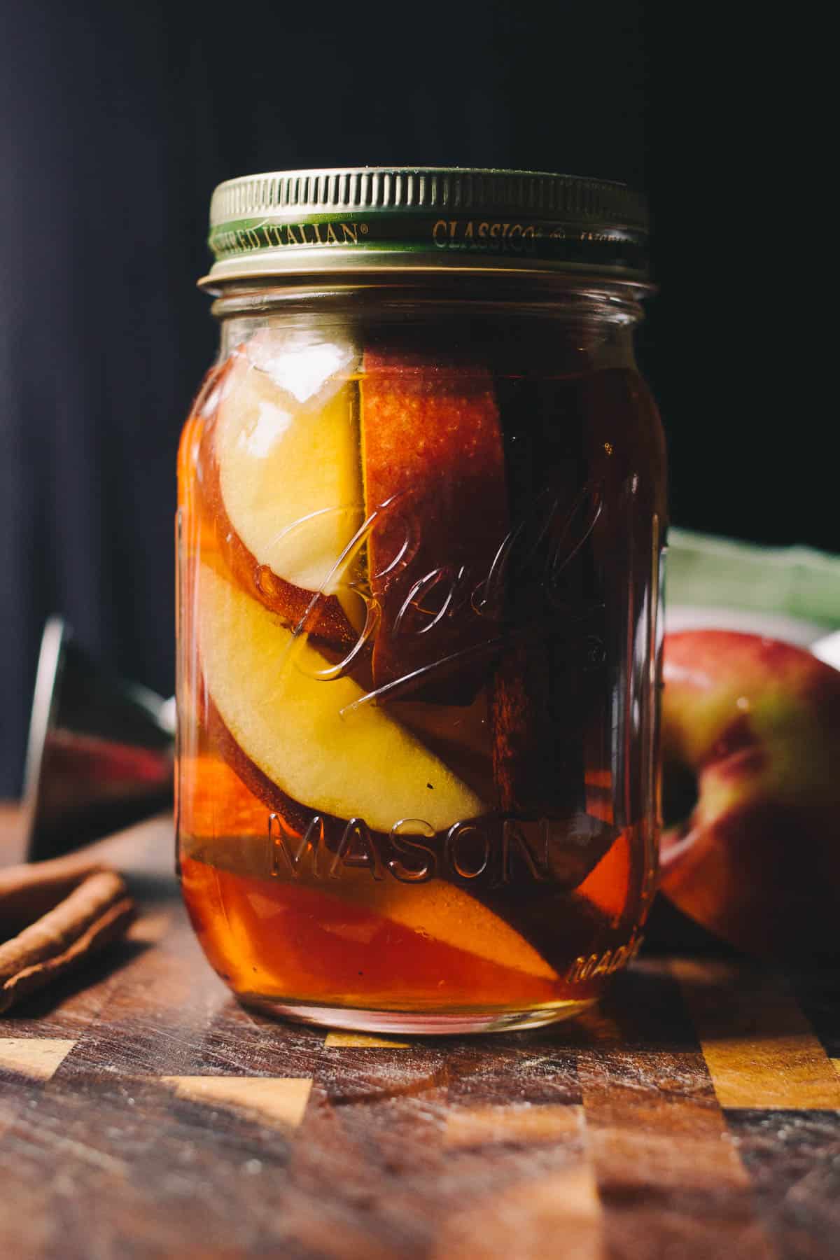 ball mason jar with apple and cinnamon sticks with bourbon 