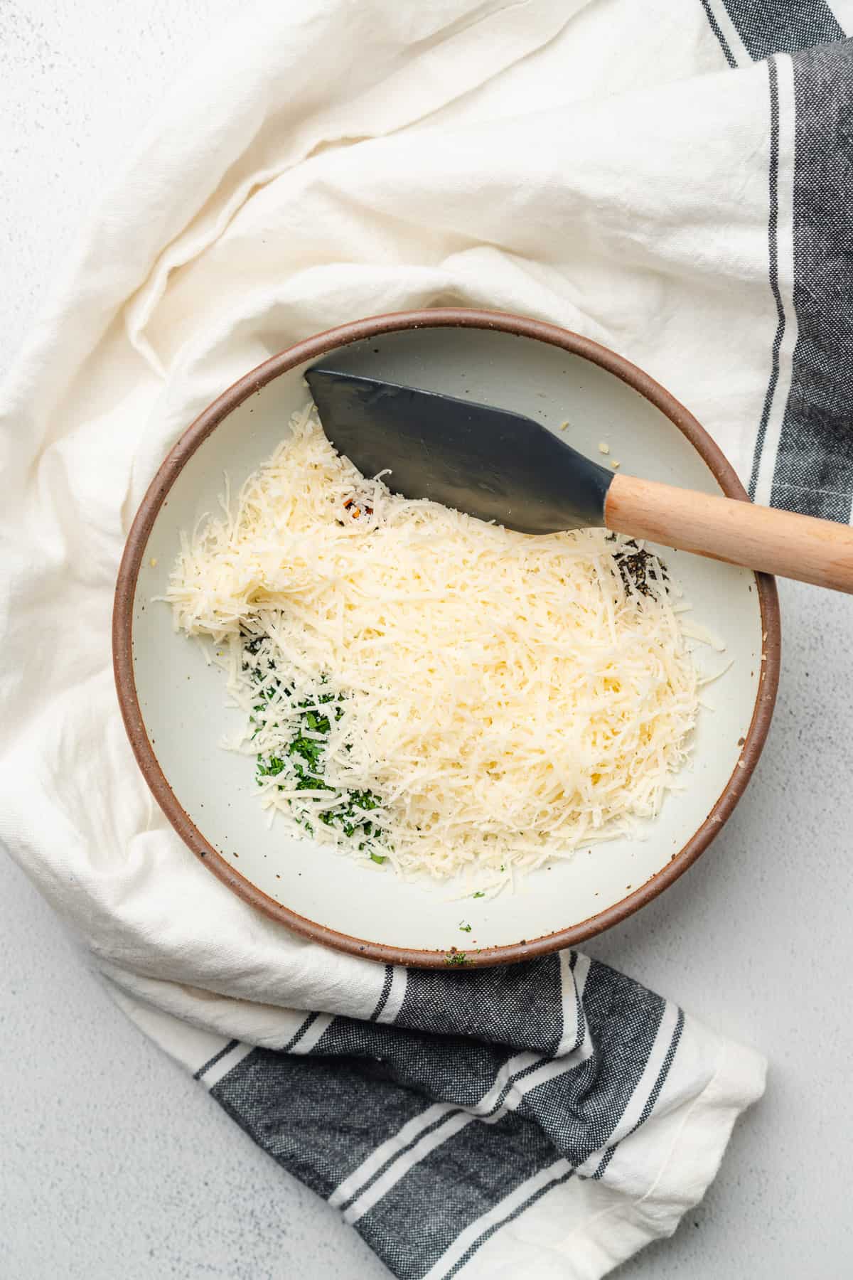 seasonings, herbs, garlic, butter and parmesan cheese in a bowl with a small rubber spatula 