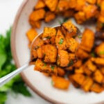 air fryer sweet potato cubes on a spoon seasoned well and garnished with fresh parsley