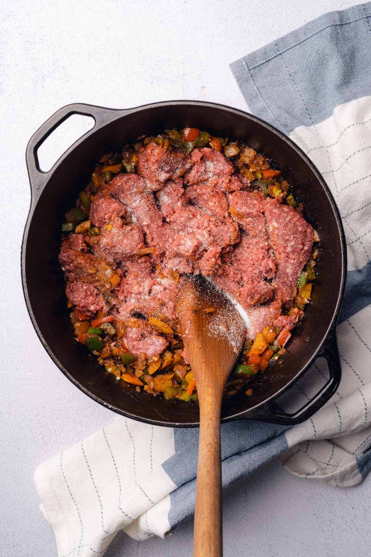 raw ground beef in a pot with seasonings and peppers to make chili