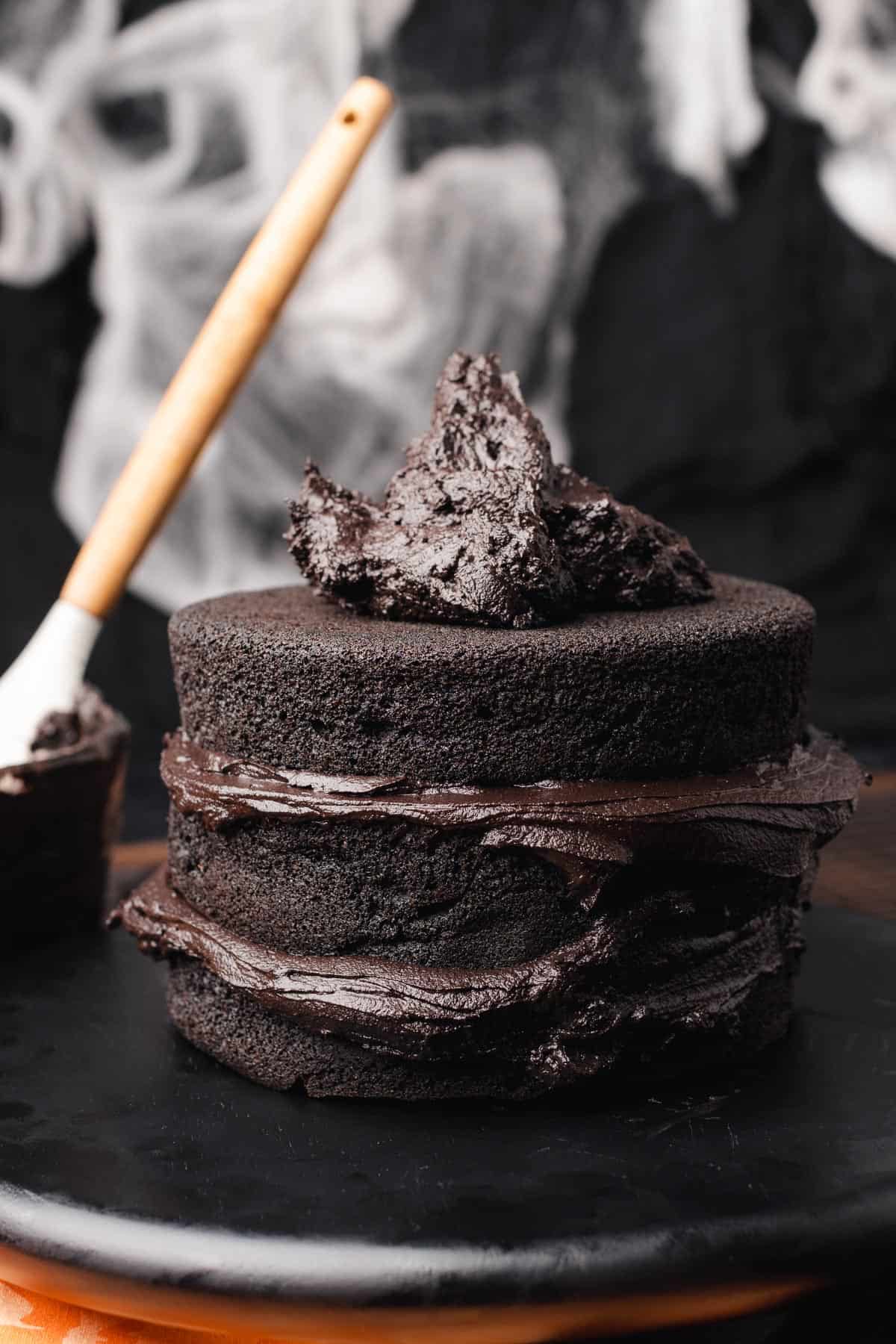 layers of a black velvet cake with dark chocolate cream cheese frosting