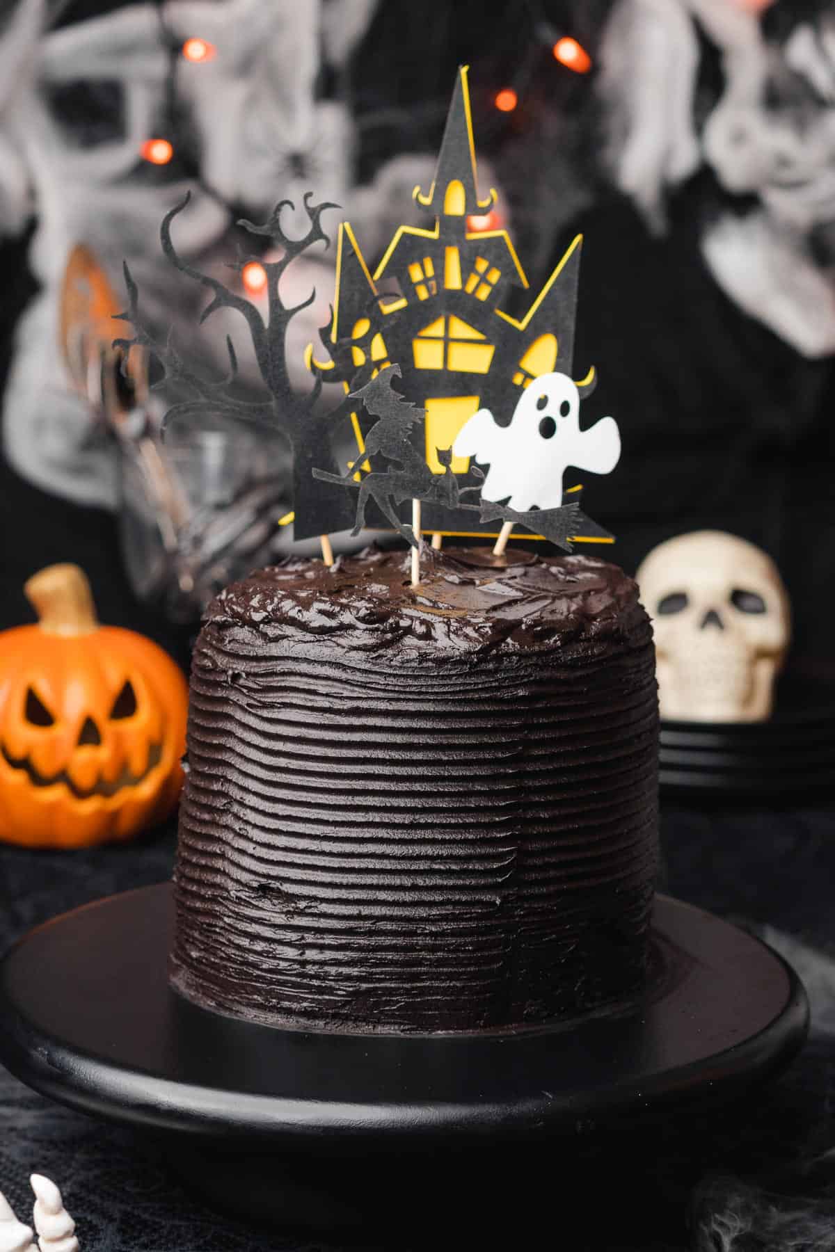 super spooky Black Velvet cake  with 4 layers, and spooky Halloween decorations surrounding it