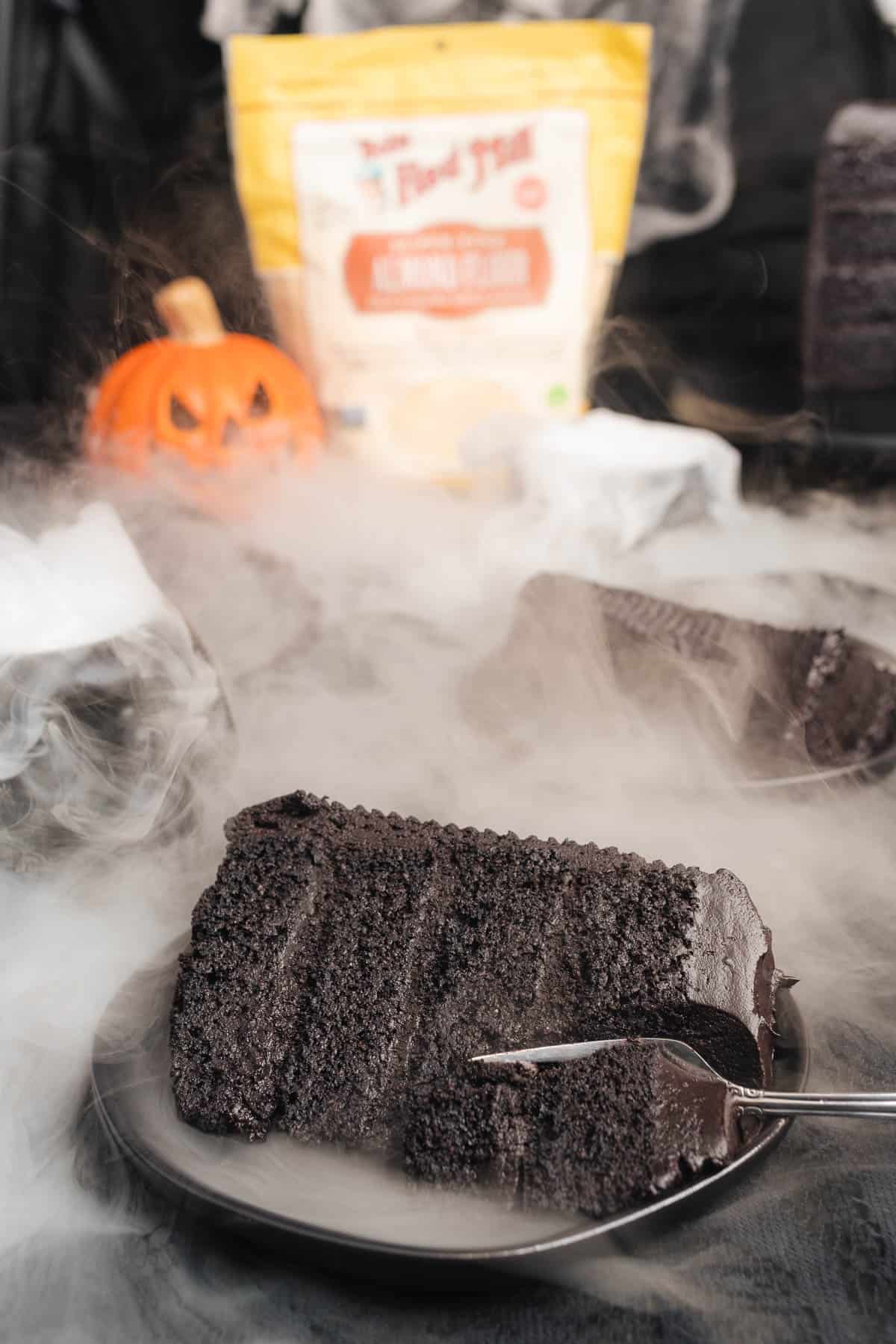 black velvet cake slices on black plates with a spooky halloween scene in the background and a bag of bob's red mill almond flour