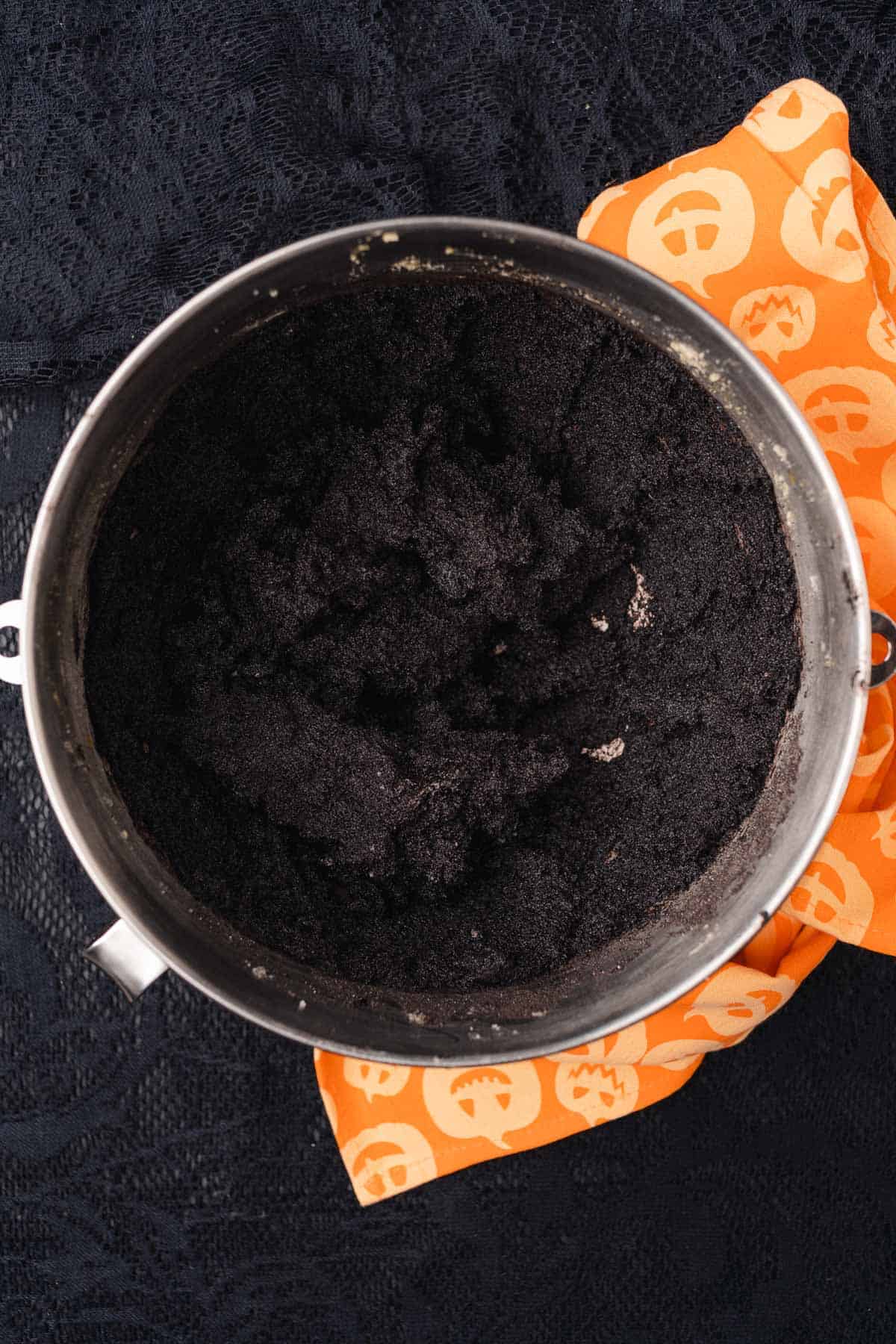 cake batter mixture in a mixing bowl with a halloween towel nearby