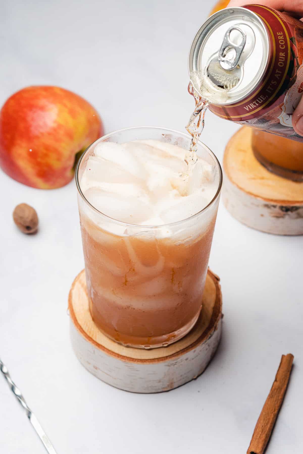 pouring dry apple cider into a cocktail glass