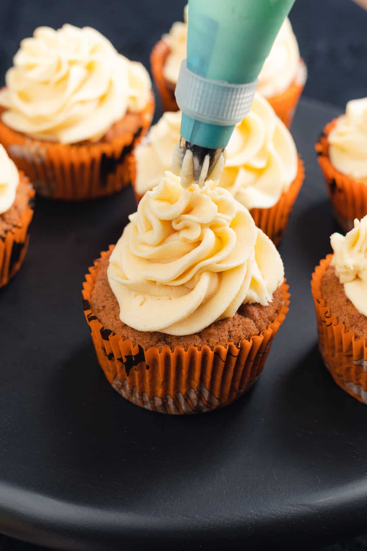 frosting a spiced cupcake with cream cheese frosting