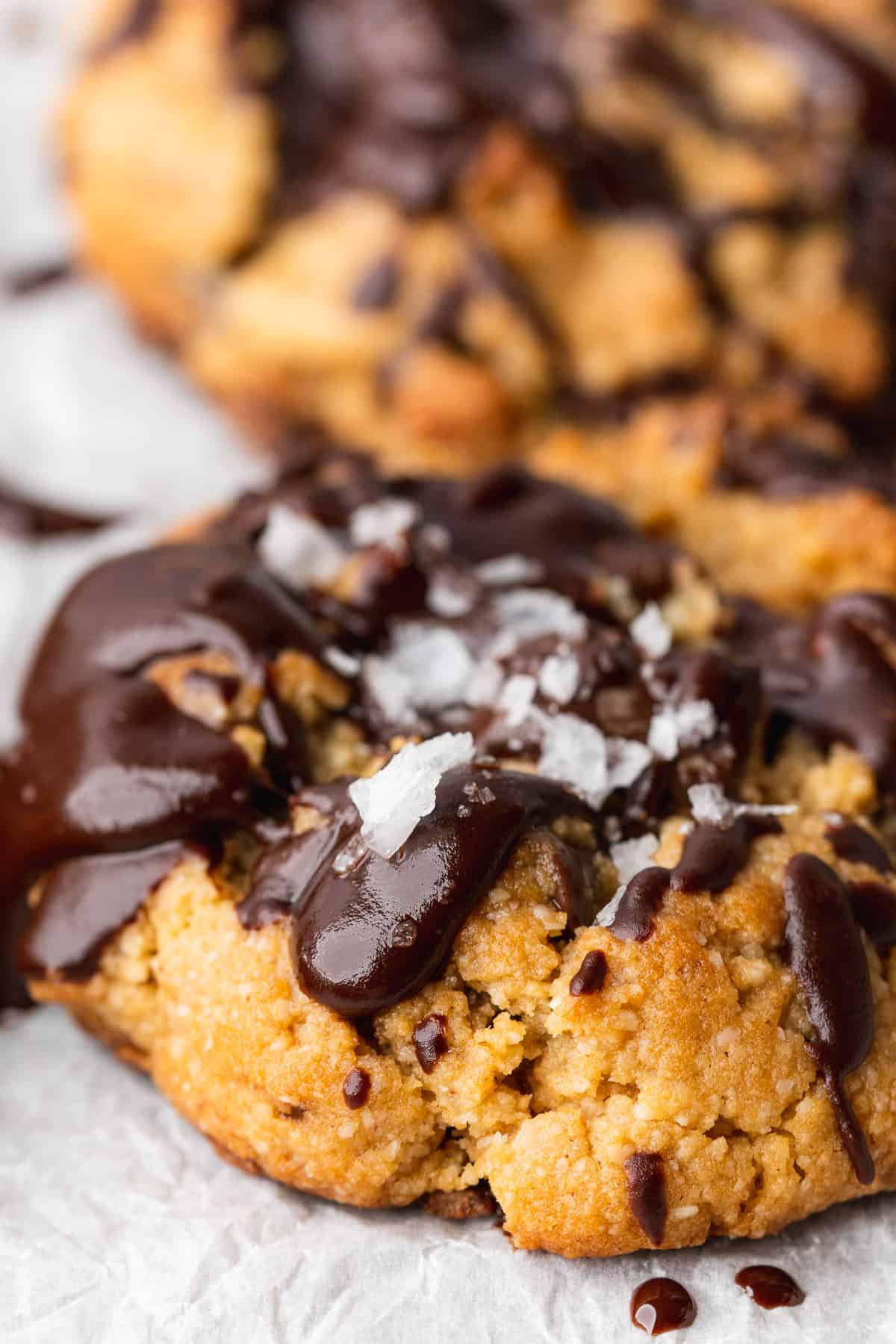 close up shot of a large keto peanut butter chocolate chip cookie with chocolate drizzle and flakey sea salt