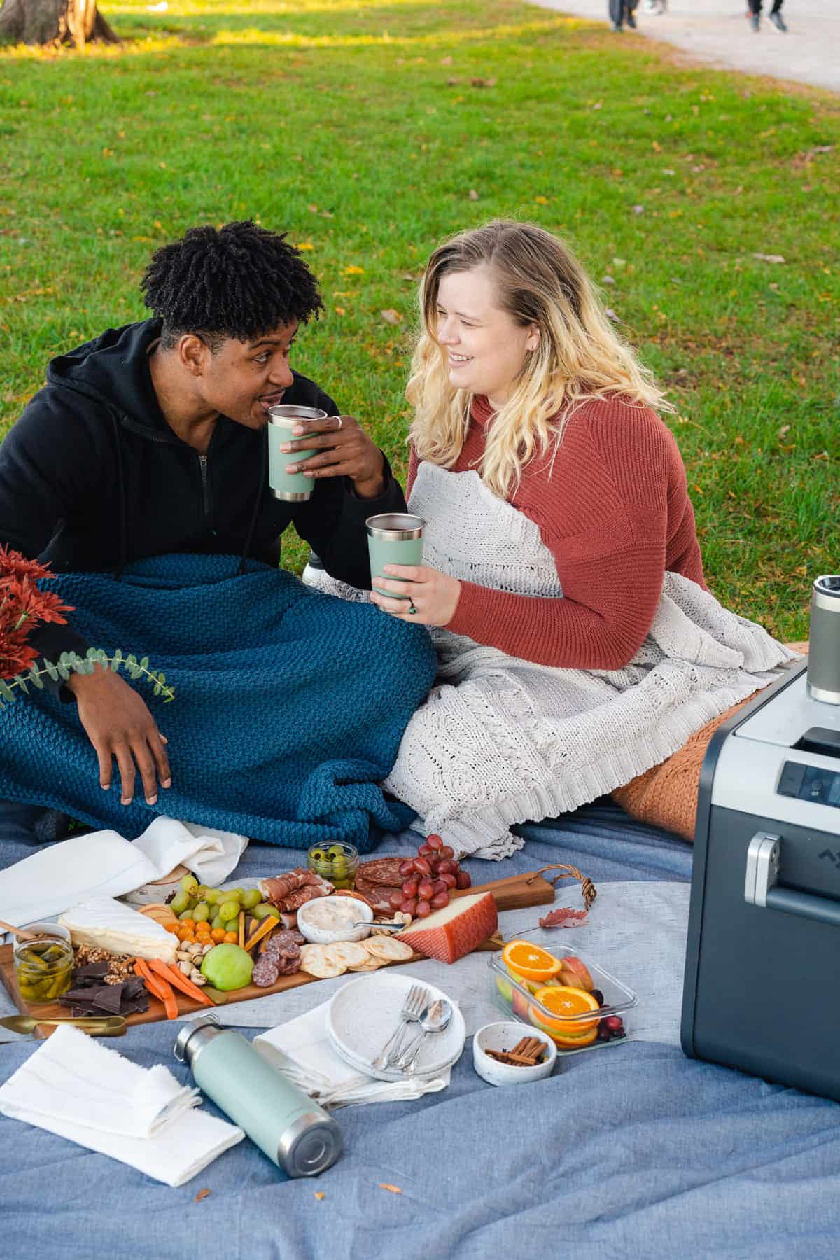 a couple laughing and talking while drinking mulled wine with a charcuterie spread in the fall