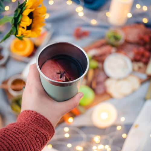 cozy fall picnic with twinkle lights, a charcuterie board, fall flowers and mulled wine