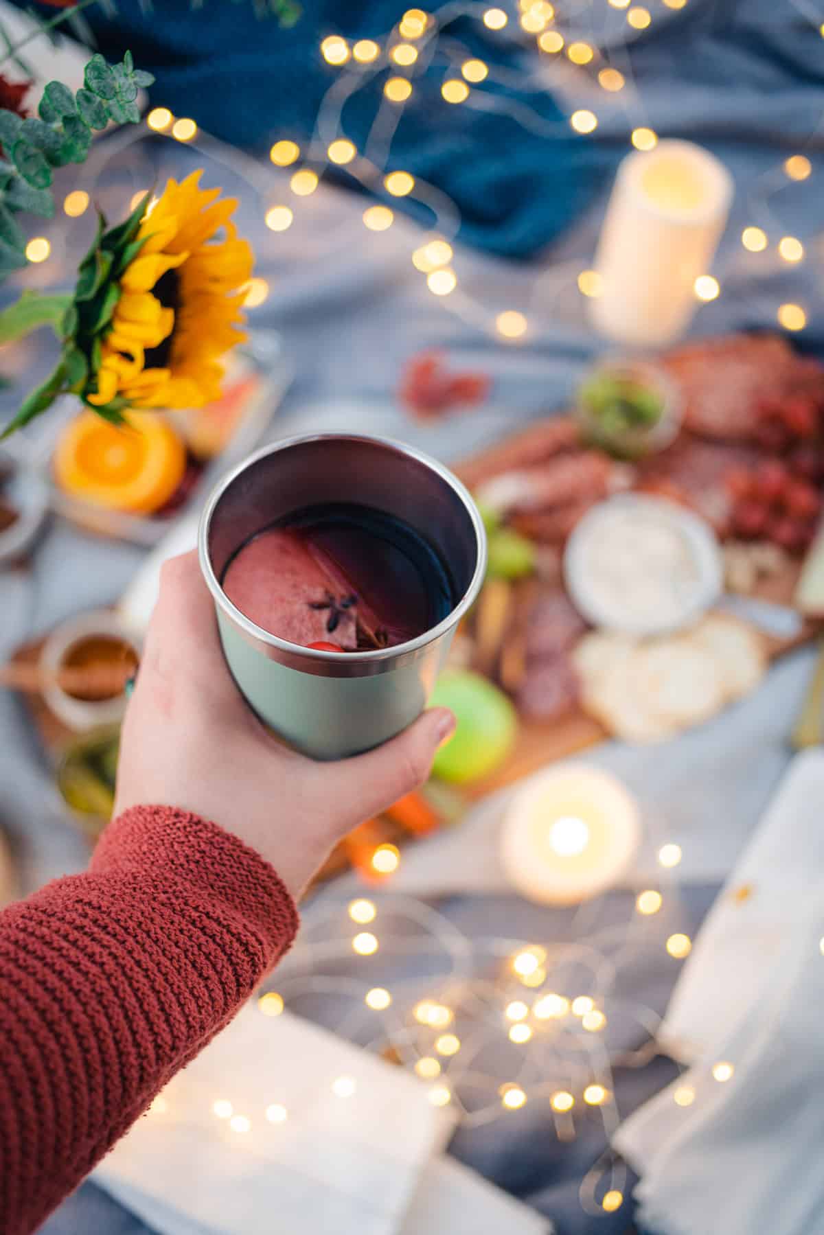 cozy fall picnic with twinkle lights, a charcuterie board, fall flowers and mulled wine