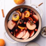 making mulled wine in a dutch oven with fruit and warming spices