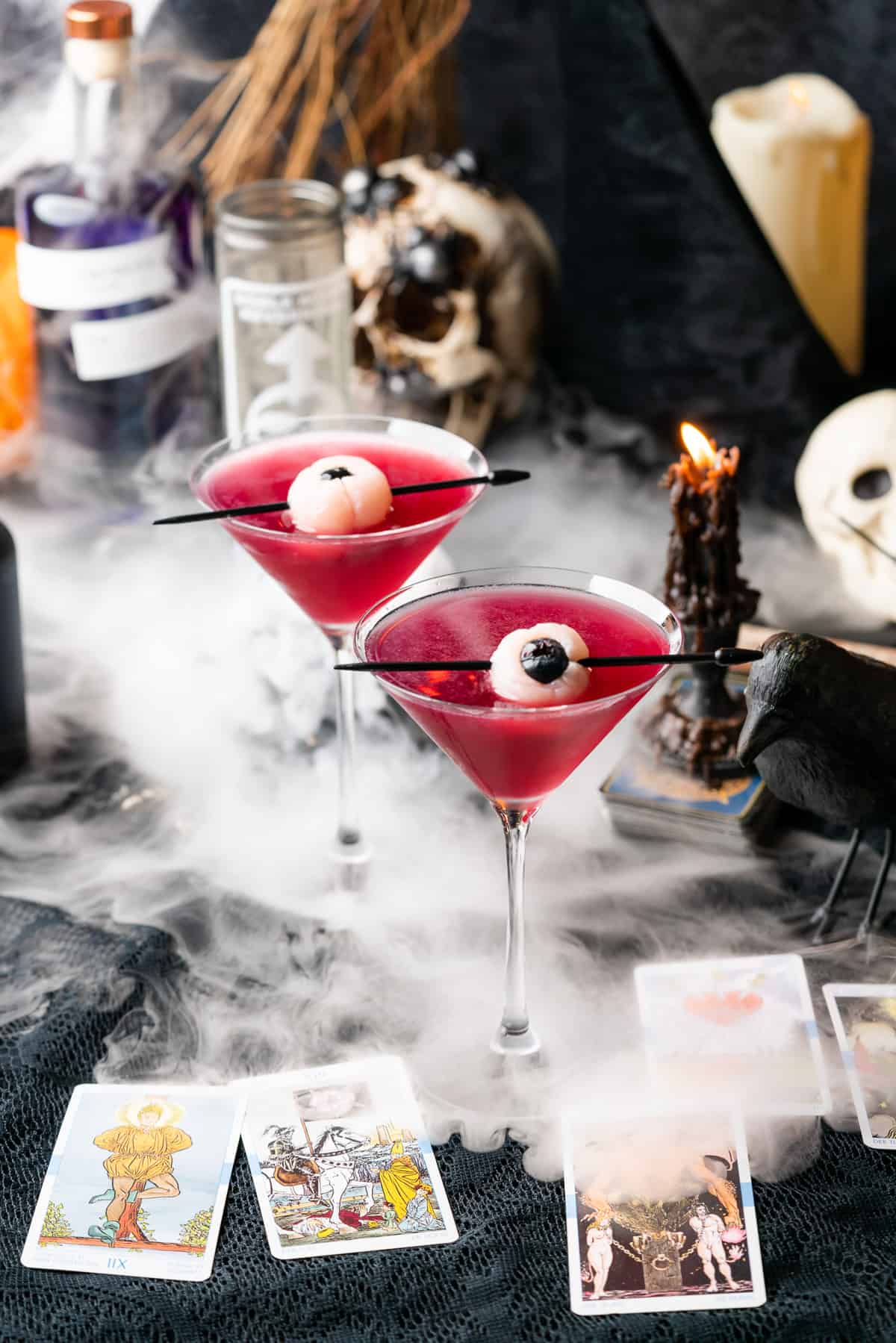 spooky purple people eater cocktail with lychee eyeballs, dry ice, skulls and black candles